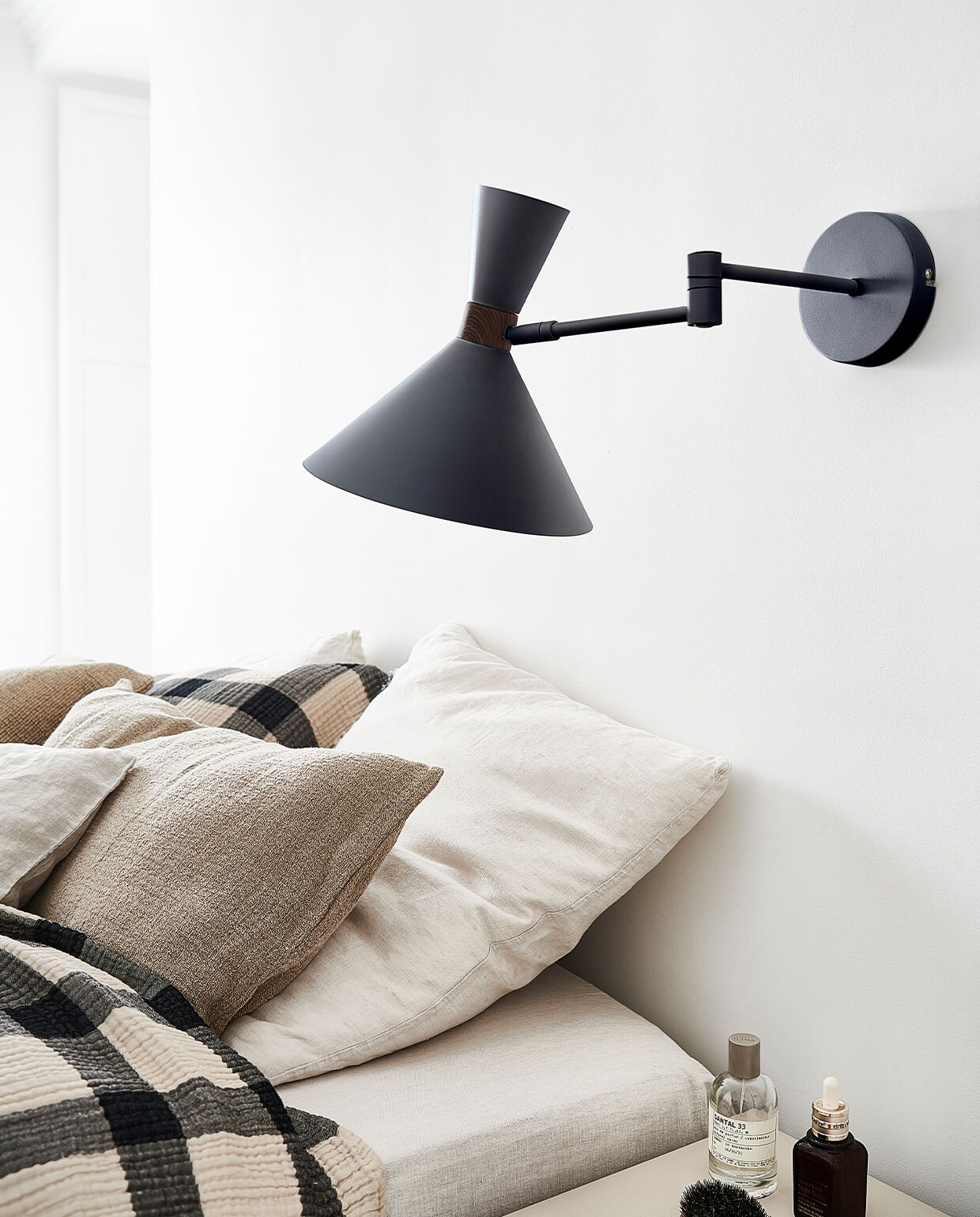 Matzwarte metalen wandlamp Hoodies, 25x25x50,5 cm € 89,95 (ook verkrijgbaar in mat zandgrijs) | M.m.v. hm.com (geblokt plaid en bijpassend kussen), zarahome.com (kussens). Overig privébezit.