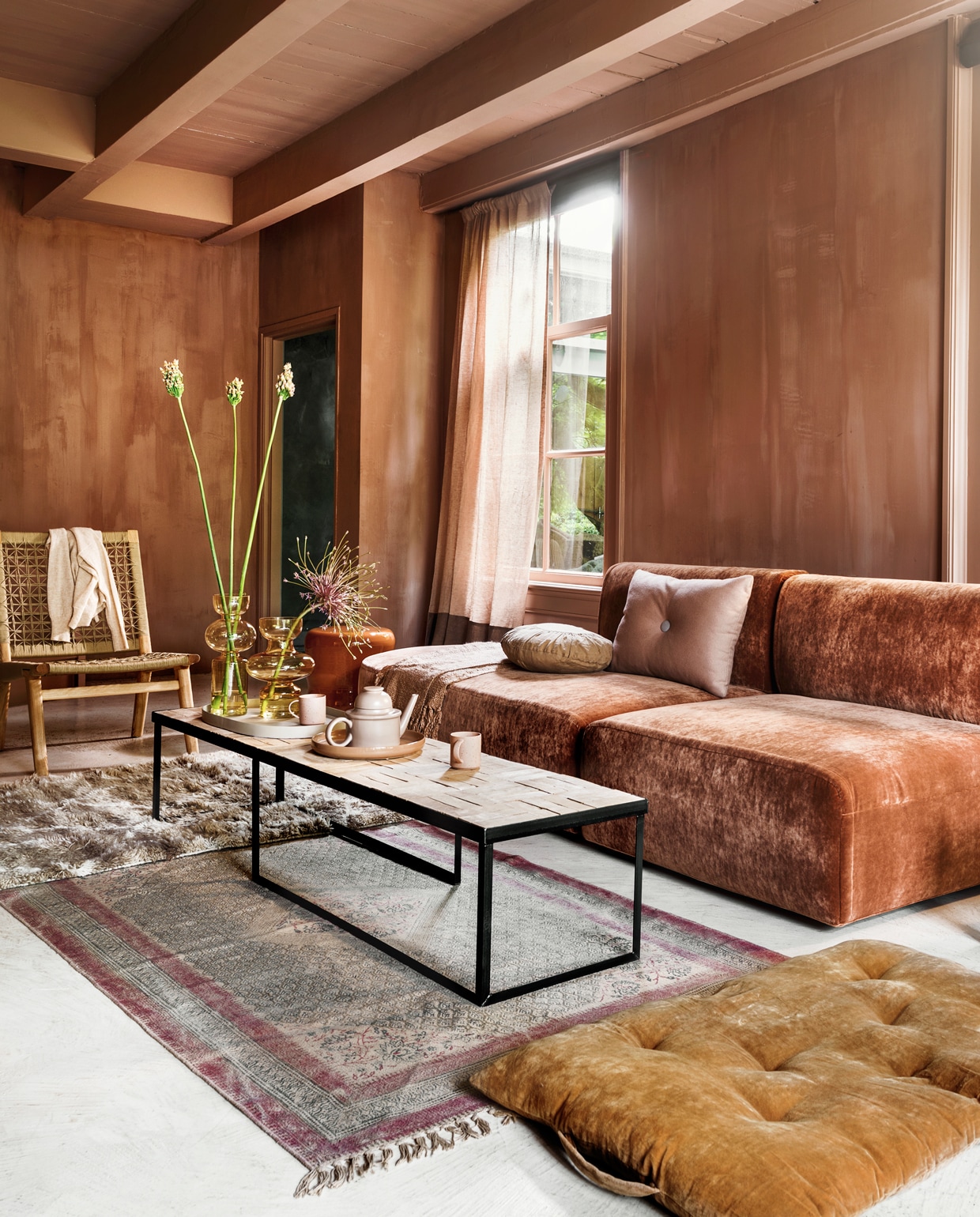 Elementenbank Bow van Cassina in sleetse velours Gordon, vanaf € 2150,- per element (frozenfountain.com). Keramieken ronde bijzettafel van Marie Michielssen vanaf € 345,- (serax.com). Fauteuil van touw en hout € 700,- (sukha). Stalen salontafel met blad van terra tegels, 165×42,5×34 cm, vanaf € 795,- (boxworx.nl). Hoogpolig vloerkleed 180×120 cm € 439,- (hkliving). Vaal kleed met print, 180 x120 cm € 195,- (iblaursen.dk). Matraskussen van geel velours € 62,- (deens). Gordijn van linnen Sutton House Reloaded, kleuren CH2351/022 en 023 van Chivasso, kamerhoog, breedte 310 cm per meter € 144,50 (jab.de). Op de bank: plaid van Malagoon € 39,95, rechthoekig kussen van Hay € 79,- (eijerkamp), rond kussen van Madam Stoltz € 34,50 (vtwonen.be). Op tafel: ovaal zandkleurig dienblad van Serax € 61,-, zalmkleurig dienblad van Bloomingville € 24,95, theepot van Normann Copenhagen € 80,50, glazen vazen van Mica, € 26,95 en € 27,95, (vtwonen.be). Mokken met oor van hkliving € 7,75 (eijerkamp). Kalkverf kleur Cypria, per liter vanaf € 45,85 (brechtmurreatelier).
