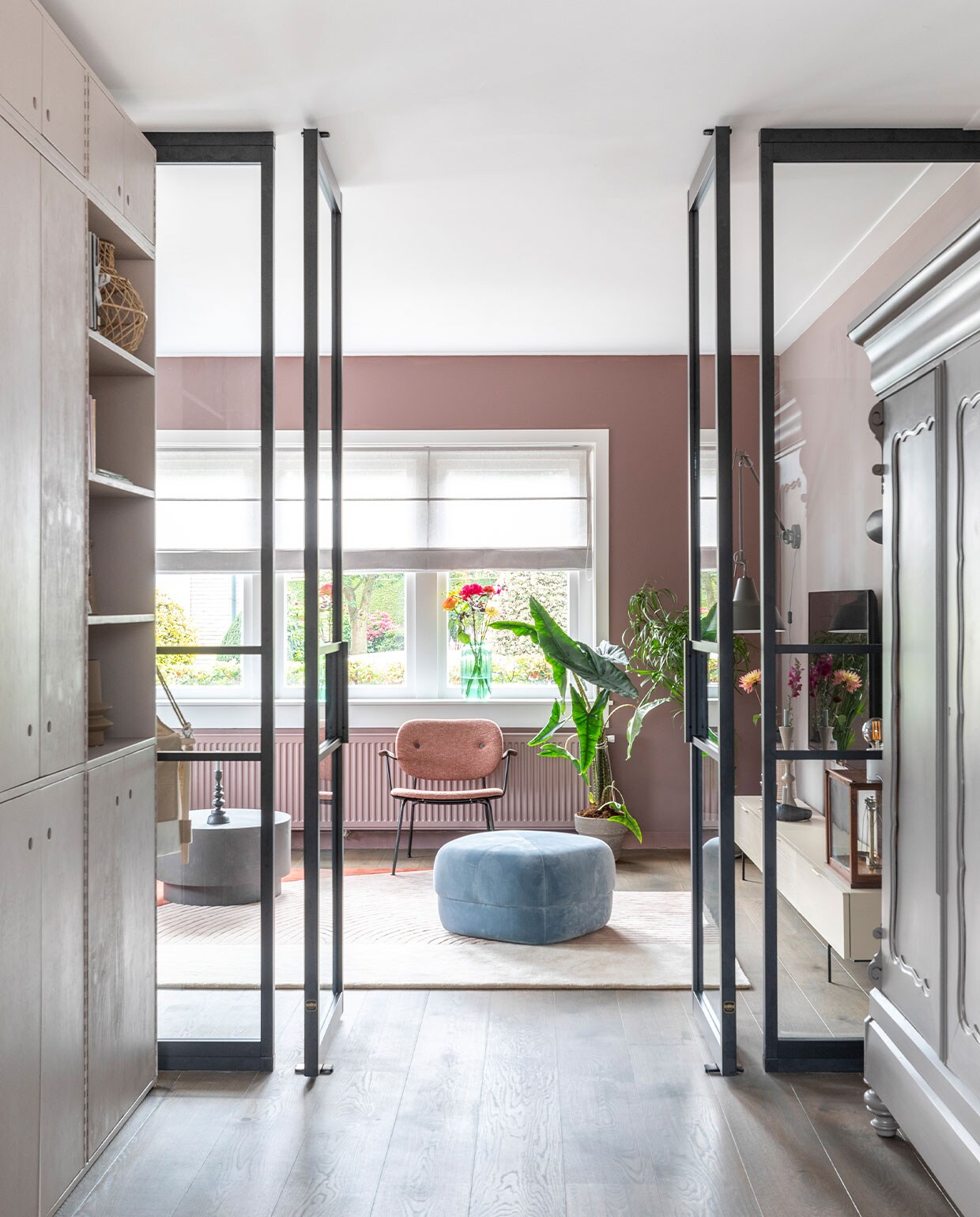 Kast links op maat gemaakt, prijs op aanvraag (com-anders), geverfd met Flexa Creations lak Perky Limestone (flexa). Poef van Norman Copenhagen € 660,-, vloerkleed Layered € 1290,-, fauteuil Co Lounge van Menu € 1230,-, salontafel van Woood € 249,- (eijerkamp). Beige vaas van Bloomingville € 49,90, bruine vaas van Bloomingville € 49,90, rieten mand van Frutas € 49,95, kandelaar op salontafel van BePureHome € 26,95, groene vaas in vensterbank van Bloomingville € 49,90 (vtwonen.be). Antieke kast geverfd met Flexa Creations lak Spacious Grey (flexa). Stalen taatsdeuren van keuken naar woonkamer op maat gemaakt, prijs op aanvraag (gewoongers). Overig privébezit.
