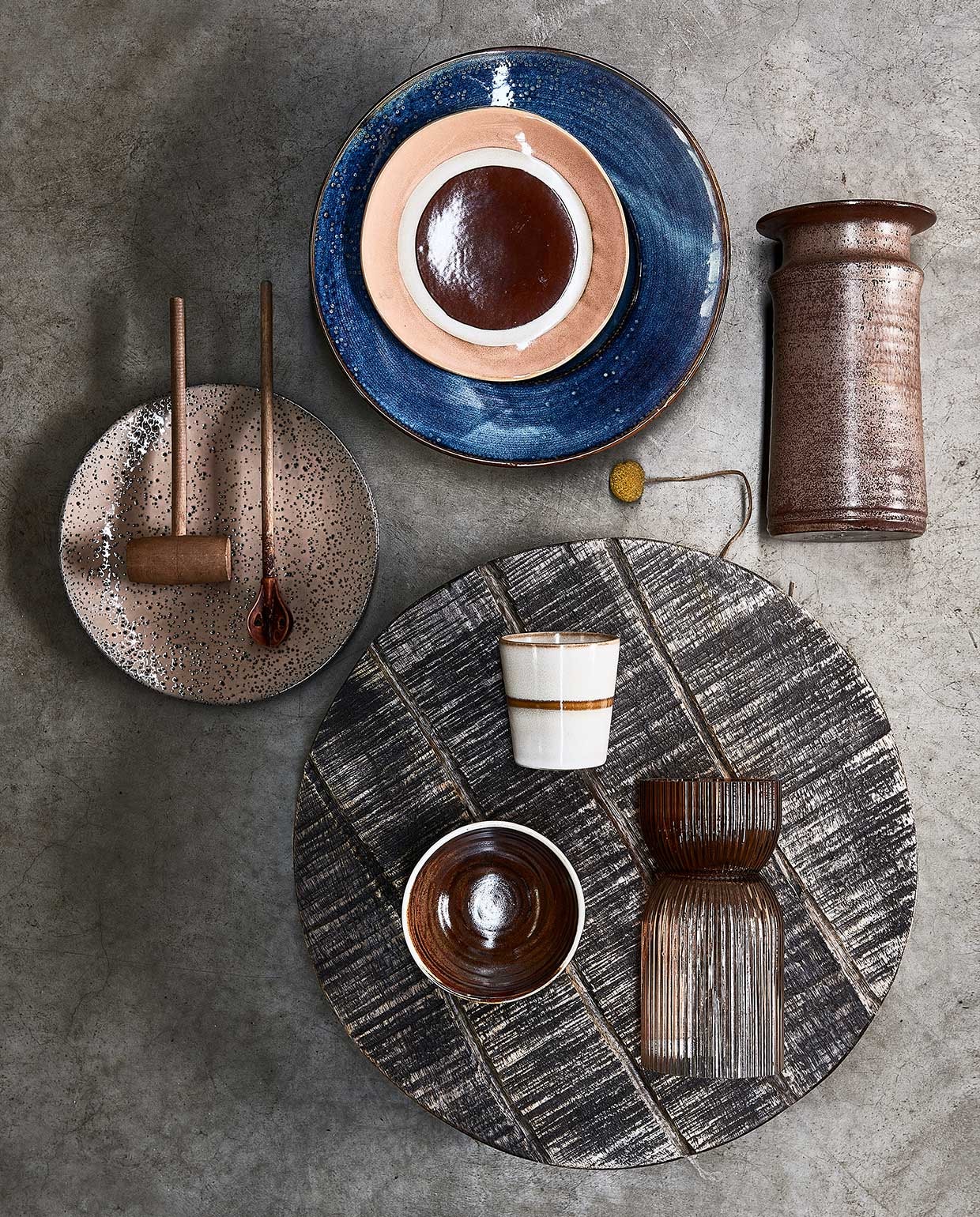 Pastabord blauw, 28,5 cm (Ø) € 24,95, dessertbord met cirkel, 17,5 cm (Ø), per 2 € 16,95, klein bord taupe, 22,5 cm (Ø), per 2 € 19,95, bruine kom, 11,5 cm (Ø) € 7,50, mok € 8,50 (hkliving). Houten plank 40 cm (Ø) € 44,95 (deeekhoorn.com). Vaas € 20,-, houten keukengerei per stuk € 5,- (neeflouis). Glazen ribbelvaas, 24 cm (h) € 35,99 (fonq.be).