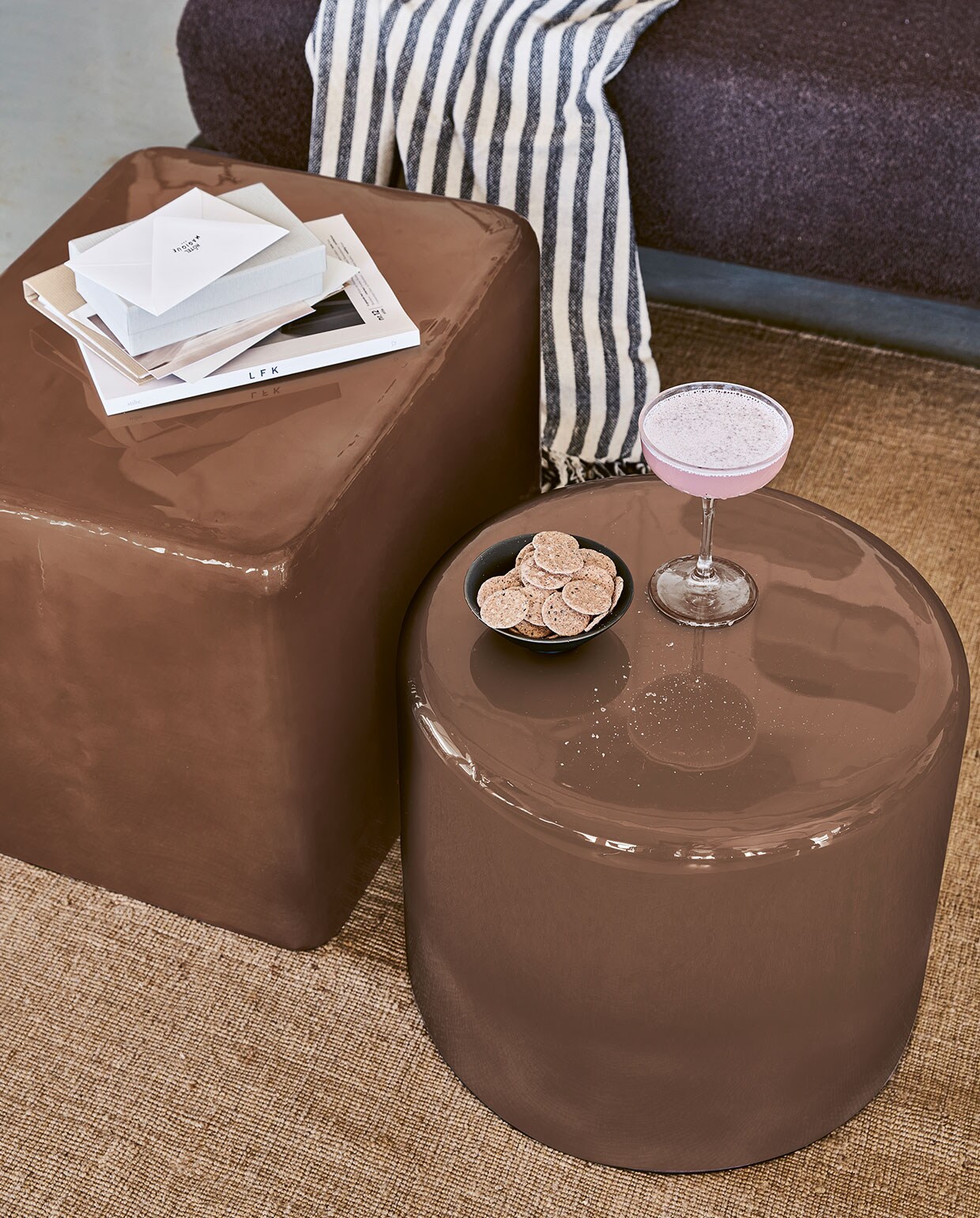 Roségoudkleurige metalen bijzettafel/poef, rond 43×36 cm (Øxh) € 149,-, rechthoekig 36x43x55 cm € 199,- (hxbxd). Zwart-wit gestreepte plaid van chambray met geknoopte franjes, 130×170 cm (bxl) € 49,95.M.m.v. Karwei (vloerkleed van vtwonen). Overig privébezit.