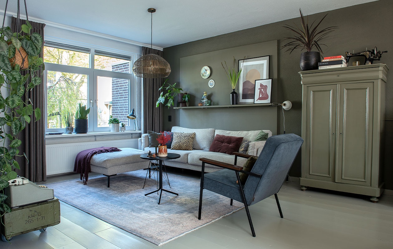 Muurverf Camouflage van Flexa. Bank Cosy Villa van Casba Wonen. Stoel Karwei, tafel Trampoliere van Midj. Kast, grote vaas en borden kringloop. Hanglamp Light &amp; Living, vloerkleed Volero. Posters Desenio. Bloempot op wandplank Jysk. Kussen tijgerprint van Goround, bordeauxrood van Mrs. Bloom. Klemspot Ikea, oranjerode vaas Madam Stoltz. Bureaulamp, Chinese vogel en vis van de groothandel. Overig onbekend.