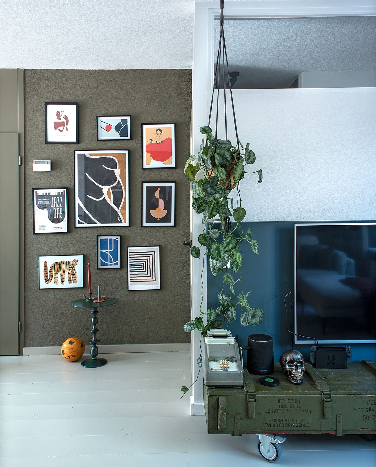 Muurverf Camouflage van Flexa en Vintage blauw van Karwei. Posters Desenio, tafel Karwei, kandelaar rechts groothandel. Speaker Harman Kardon, schedel spaarpot Kare Design. Planthanger Intratuin. Leger munitiekist, telmachine en kandelaar links van de kringloop.