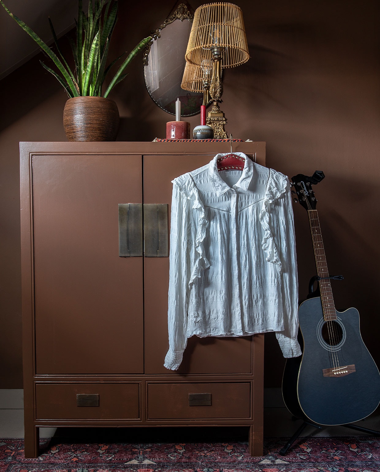 Verf wand- en kast bruin IG PS 1051 van Karwei. Chinese kast, lamp en spiegel van de kringloop. Kleed Leen Bakker. Plantenpot Intratuin. Kandelaars onbekend. Gitaar Richwood..