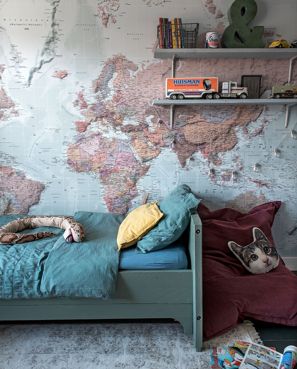 Bed zelfgemaakt van oude planken, kleur verf bed onbekend. Behang wereldkaart Photowall. Bedlinnen Jysk. Slang Ikea, kussen kat Zeeman, zitzak Leen Bakker, draadmand en &amp;-teken Loods 5. Vrachtwagen via Bas’ werk, oude auto’s van Bas. Overig onbekend.