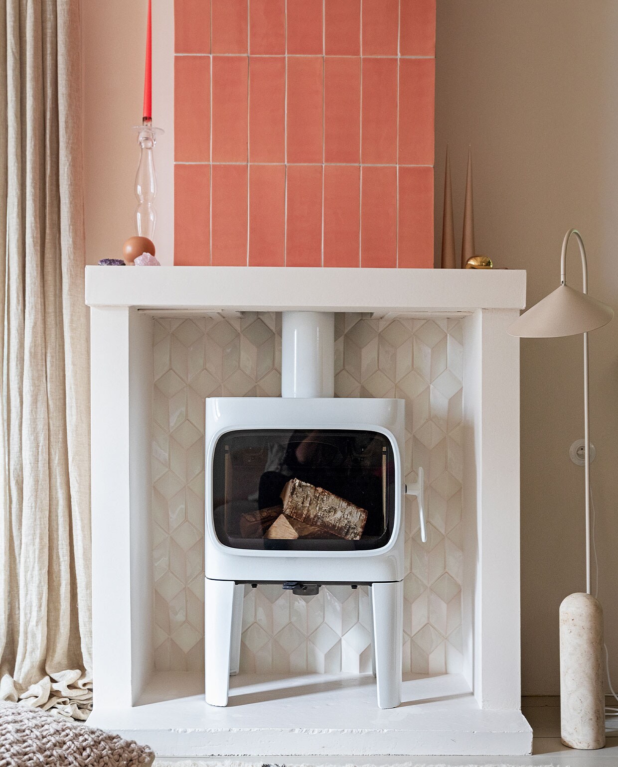 Houtkachel Jøtul F305. Tegels 10×30 cm kleur Flamingo Baby en witte tegels Constellation kleur Eggshell White via Quintalisque. Kussen Sukha. Lamp en kiezel Ferm Living. Glazen kandelaar herkomst onbekend. Kaarsen Ester &amp; Erik.