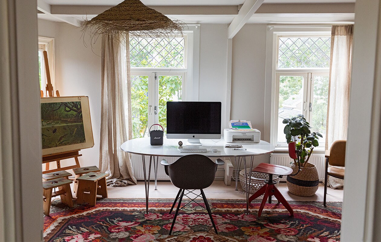 Bureau Fritz Hansen. Stoel Eames via Vitra. Rozenkelim Raw Materials. Melkkrukken eigen ontwerp Isi i.s.m. Geralt Ploegstra. Schoolplaat In sloot en plas antiquair. Lamp Household Hardware. Muziekbox Marshall. Eikenhouten vloer met whitewash olie Parketservice Alkmaar. Wand en plafond kleur Porcelain Mould van Flexa. Fotolijst van oma. Schildersezel Mabef. Gordijnroede zelfgemaakt. Gordijn herkomst onbekend.