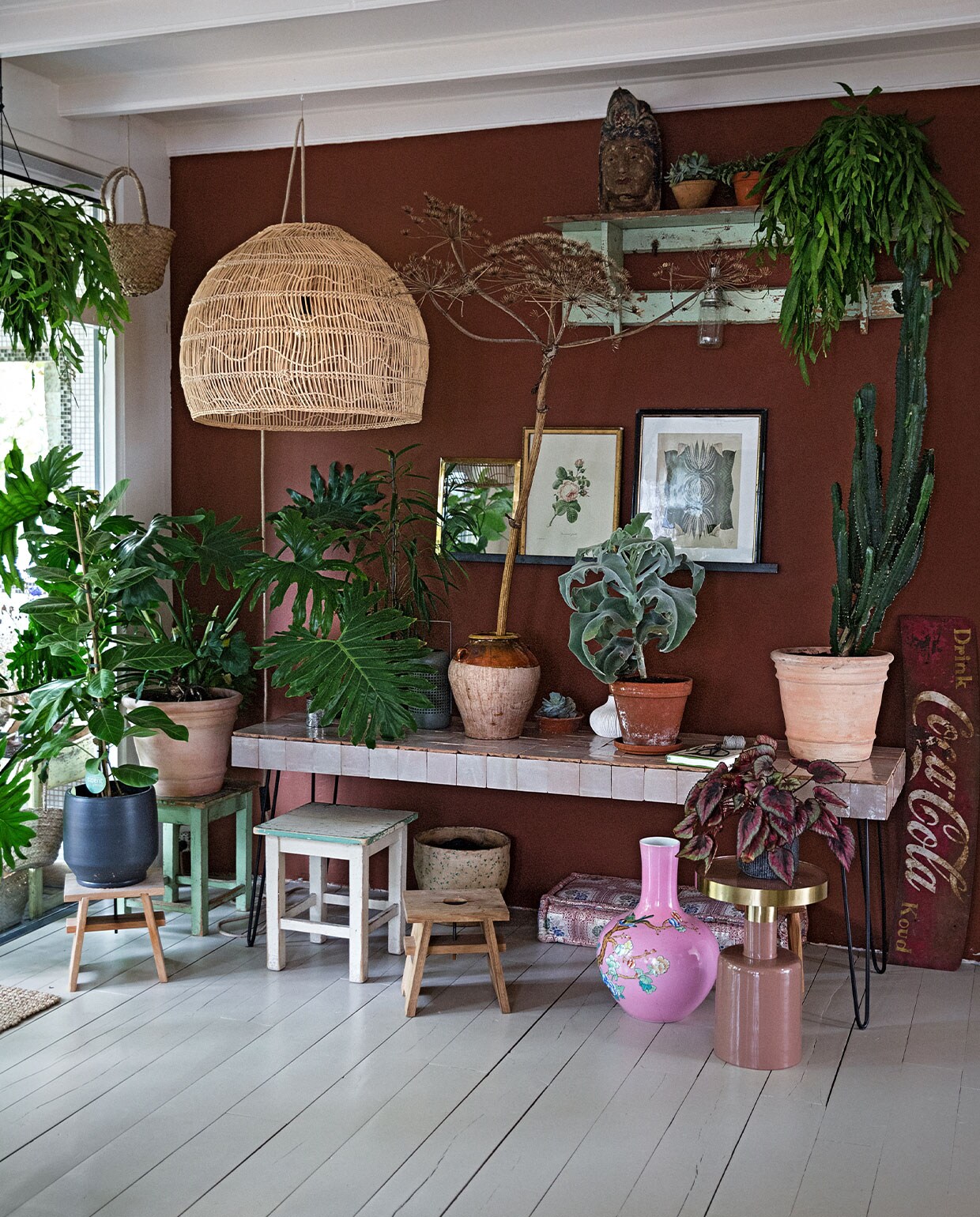 Tafel zelfgemaakt (tegels Household Hardware en hairpin-poten bol.com). Rieten lamp HKliving. Coca Cola bord op straat gevonden. Bijzettafel met gouden blad Zuiver. Roze vaas van Pols Potten via Wim van Assem bloembinderij. Kussen en spiegel Household Hardware. Prullenbak cadeau gekregen. Melkkruk eigen ontwerp Isi i.s.m. Geralt Ploegstra. Krukken achter Loods 5. Zwarte bloempot vtwonen. Olijfpot cadeau gekregen. Pot rechts en terra pot Ranzijn. Boeddha hoofd, schilderij midden en kapstok brocante markt. Schilderij rechts Hanneke van de Pol via Artwall Collection. Manden met hangplanten meegenomen uit Ibiza.