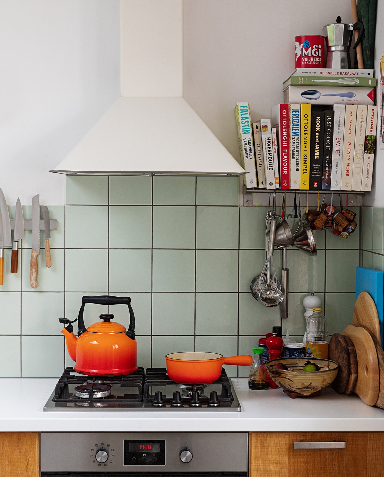 Oranje fluitketel en pan Le Creuset. Messen Suncraft, Opinel en Dille &amp; Kamille. Kookboeken Ottolenghi, Jamie Oliver, Sergio Herman, Yvestown in de keuken, De Zilveren Lepel. Snijplanken Hay, Ikea en Serax. Peper- en zoutmolen Peugeot. Soeplepel Brabantia. Hangend rvs keukengerei Dille &amp; Kamille. Percolator tweedehands. Schaaltje van een pottenbakkersmarkt. Afzuigkap en oven Ikea. Ovenhandschoen Kook. Pollepel Kookhuis aan de Maes.