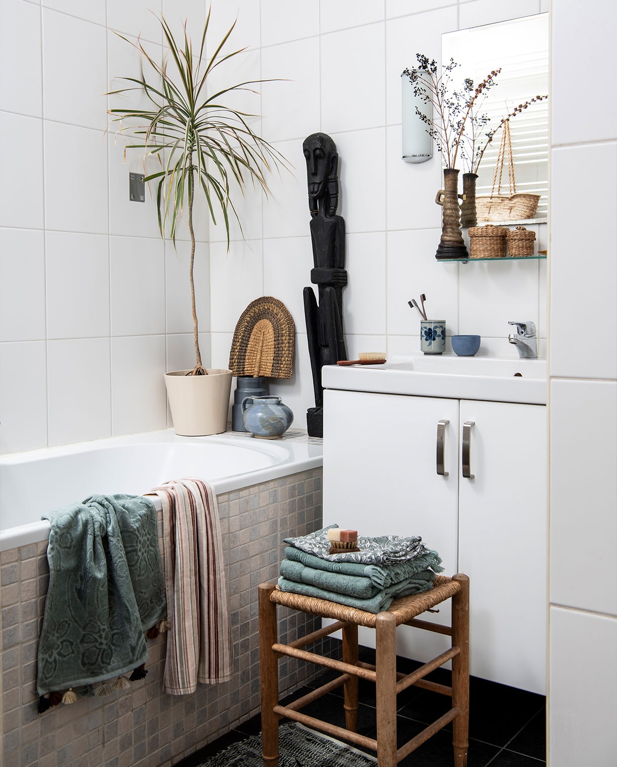 Vaas met droogbloemen, rieten manden, Afrikaanse kunst, kruk, tandenpoetsbeker tweedehands. Keramische pot D&amp;M Deco. Handdoeken Zara Home, badmat Søstrene Grene. Massageborstel Huishoudwinkel. Tanden- borstels Meraki. Plant Dracaena. Overig herkomst onbekend.