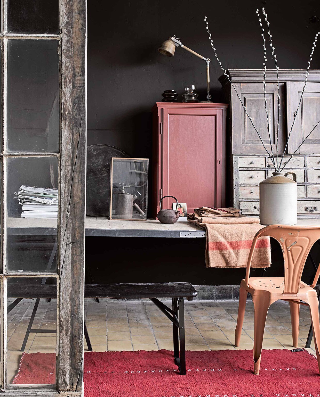 Op de muur krijtverf Jungle per liter € 22,- (Home made by). Wollen vloerkleed 90×180 cm € 299,- (Room 2a). Kast € 95,- (Combitex), geverfd in lakverf Beaujolais per liter € 38,50 (Home made by). Tafel € 450,-, stoel € 125,-, ladekastje € 395,-, oud apparaat € 35,-, aardappelzakstof op tafel (Combitex). Houten tafellamp € 205,-, theepot € 55,-, kruik met oor € 75,-, bank als onderdeel van een set van 2 banken € 275,-, alles van Madam Stoltz (Deens). Ansichtkaart € 0,95 (Art Unlimited). Vitrinekastje € 99,- (Loft).
