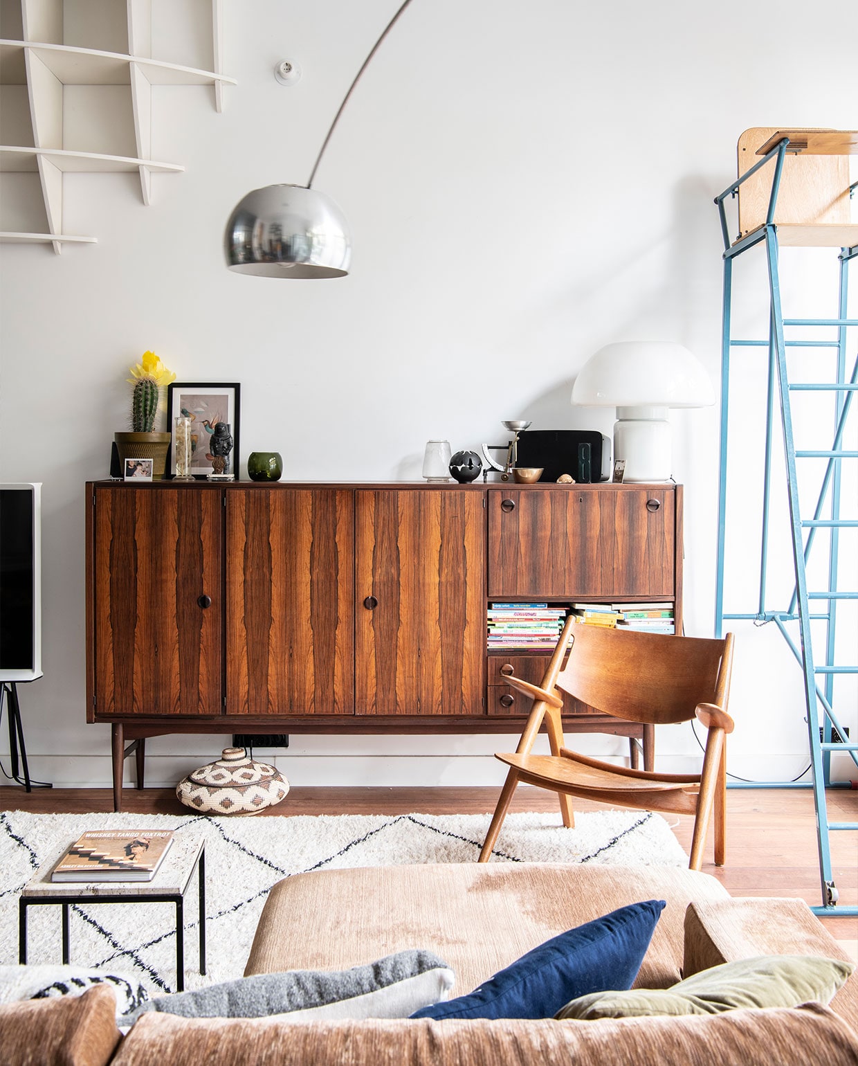 Bank Arketipo, lounge chair Hans Wegner, bijzettafel onbekend. Flos Arco booglamp, berberkleed, scheidsrechtersstoel Marktplaats. Design bolkast gekregen van de ouders van Bob. Dressoir, mushroom lamp van Elio Martinelli Marktplaats, oliebrander Aesop, brievenweegschaal en vintage glazen stolp met vleermuis souvenirs New York. Vintage bloempot DasGaaf, bloemen op sterk water in glazen erlenmeyer Het Grote Avontuur, 3D puzzel astronaut Tenue de Nîmes, waxinelichthouder Iittala, print van Dieter Braun Juniqe. Mand souvenir Bali.