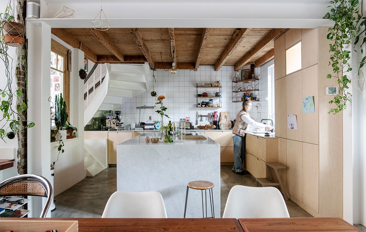 Keukenkast maatwerk, fronten Plykea, kookplaat Bora. Kookeiland en aanrecht Wessels Natuursteen. Witte tegels Meester Smeets, voeg antraciet Forbo. Koffiemachine VBM, bonenmaler Quamar, speaker Sonos, diamantlamp Dazor, weegschaal souvenir Cambodja, magnetisch messenrek Global Knives, roze beertje Bearbrick collectible, fruitschaal souvenir Suriname, vintage wandrek Tomado Marktplaats, broodplanken onbekend. Kraan Quooker. Opstap/kruk Ikea. Vintage kruk en Tulip Chairs Marktplaats, eetkamerstoel onbekend. Prullenbak Vipp. Masker souvenir Indonesië. Hexagon hanger Combo Design. Gietvloer met vloerverwarming.