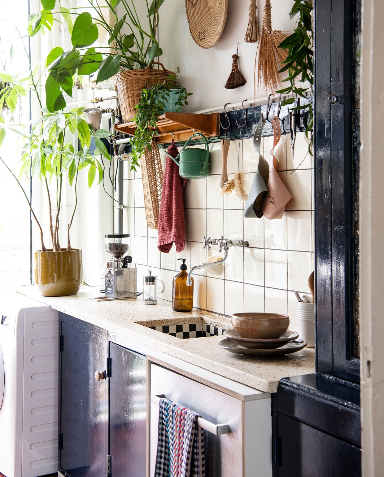 Theedoek Pluk Den Haag, borden en schaal tweedehands. Zeepdispenser Little Green Shop. Koffiemolen Nemox, bloempot DM Deco. Brabantia-gieter tweedehands, slabbetjes Achtung Baby, kwasten en borstels Dille &amp; Kamille. Planten Pachira, Monstera, Peperomia, Hoya. Overig herkomst onbekend.