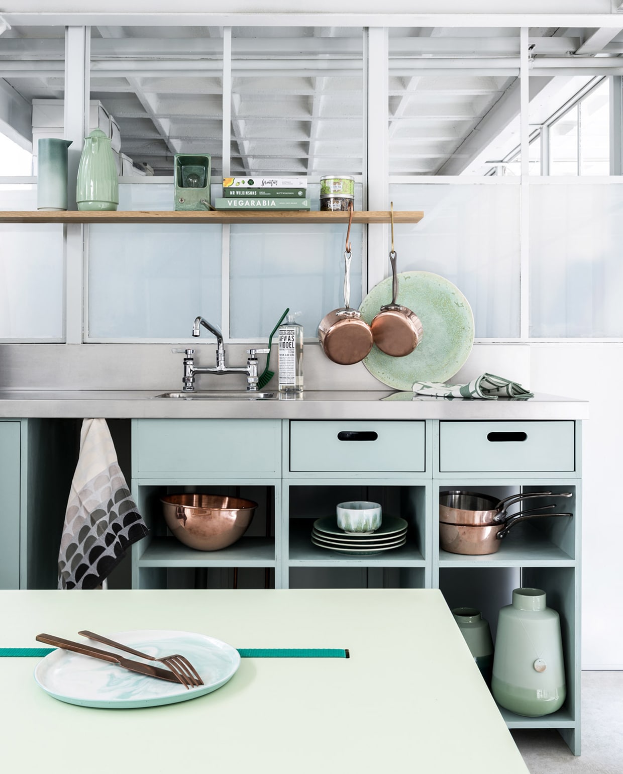 Keuken op maat gemaakt prijs op aanvraag (Sukha). Verfkleur keuken is Pigeon nr. 25 (Farrow &amp; Ball). Broodplank, kruk, kommen en bekers, grote schalen en schaal met leren lus, kleine borden , houten vaas, houten lepels en kookgerei (Sukha). Lampen (M.oss). Witte emaillen maatbekers klein en groot en pastelkleurige pannen (Riess).