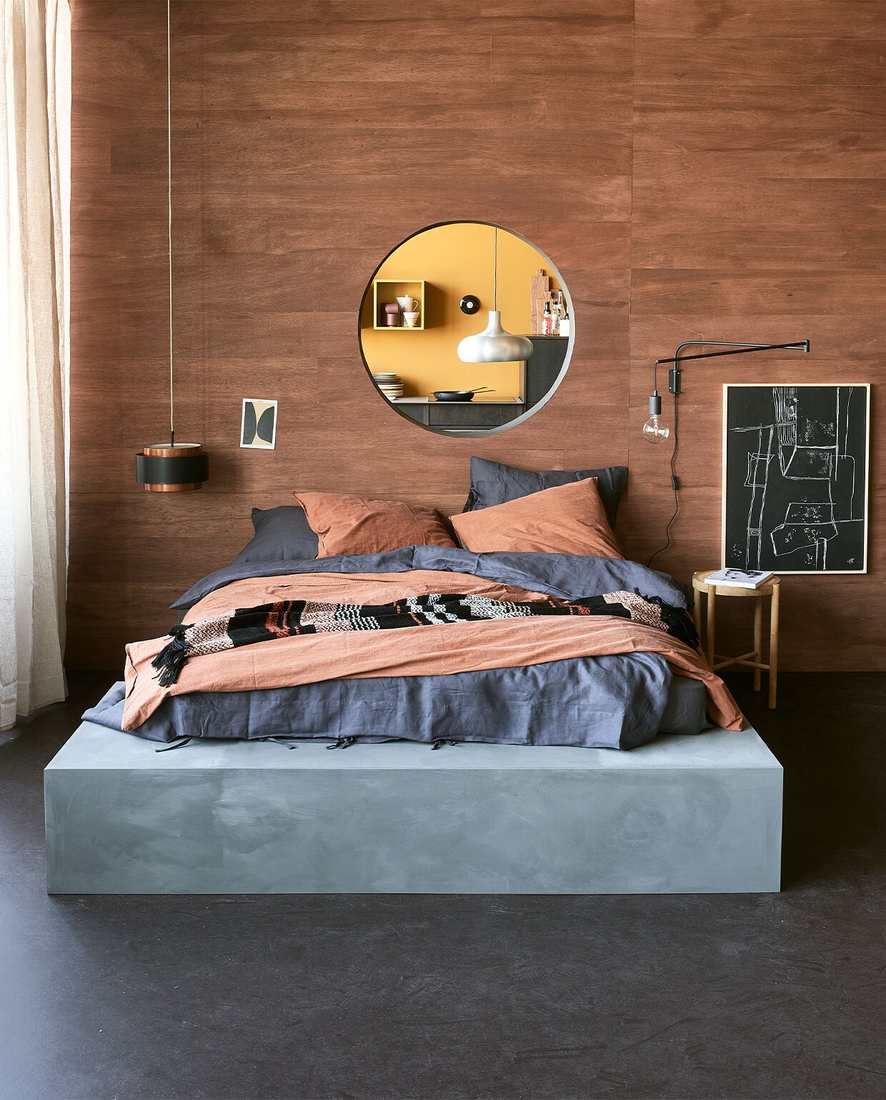 Bed op maat gemaakt en geverfd met kalkverf Blue Stone van Pure &amp; Original. De natte verf werd met een doek bewerkt voor dit effect. Steenrood dekbed­overtrek Natural Stone van vtwonen, 200×220 cm € 109,95, gestreept plaid van Malagoon, 150×125 cm € 59,95, wandlamp Line van Trio € 39,95 (vtwonen.be). Blauw dekbedovertrek Puderviva, 200×200 cm € 69,95, linnen gordijnen Dytag, 145×300 cm, set van 2 € 59,95 (ikea.com). Hanglamp € 95,- (neeflouis). Zwart kunstwerk Brutalism € 279,-, kruk met webbing zitting € 139,- (hkliving).