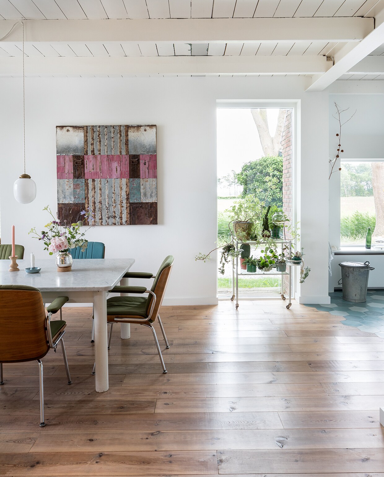 Tafel, vintage Giroflex-stoelen, vintage Siematic-keuken en Kandem-muurlampen Marktplaats. Aardewerken kandelaar rommelmarkt. Hanglamp, houten kandelaar en vaasje uit de winkel van Rixt en Clara, de Sip &amp; Clara Pop-up Store. Antieke radiator van pop-up store in Groningen. Portugese vloertegels Mosaic del Sur. Groen glaswerk rommelmarkt, pan Nicolas Vahé, bakelieten schakelaars Frummes.nl. Kunstwerk Henk Kastelijn, tegel zeepaardje op afzuigkap rommelmarkt. De ijsblauw geschilderde hoge deur is hergebruikt.