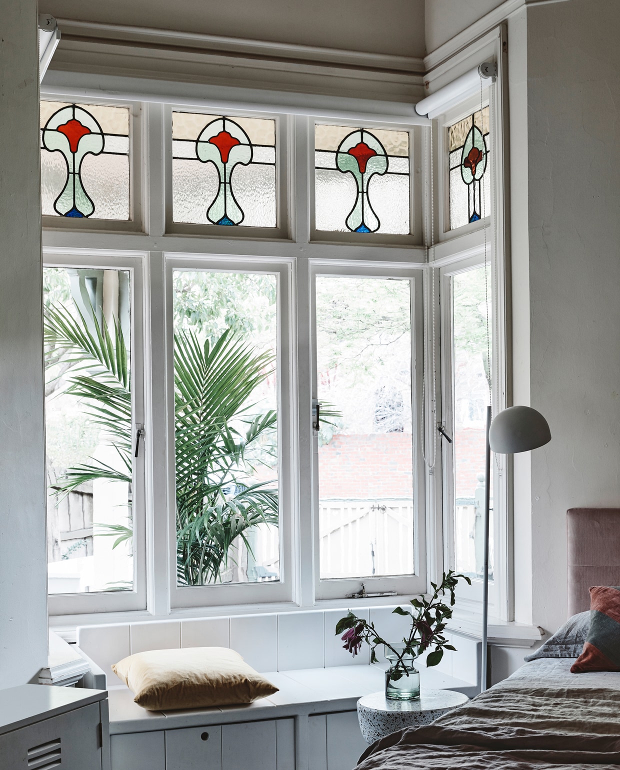In de kamer van Nina maakte Hans zelf een bank voor de nis. ‘Vroeger zat ze hier vaak met een boek, nu met haar iPhone.’ Fluwelen bedhoofd en beddengoed van House of Orange. Bijzettafel, lamp en gestreept kussen van HK Living. De badjas is een souvenir van Bali.