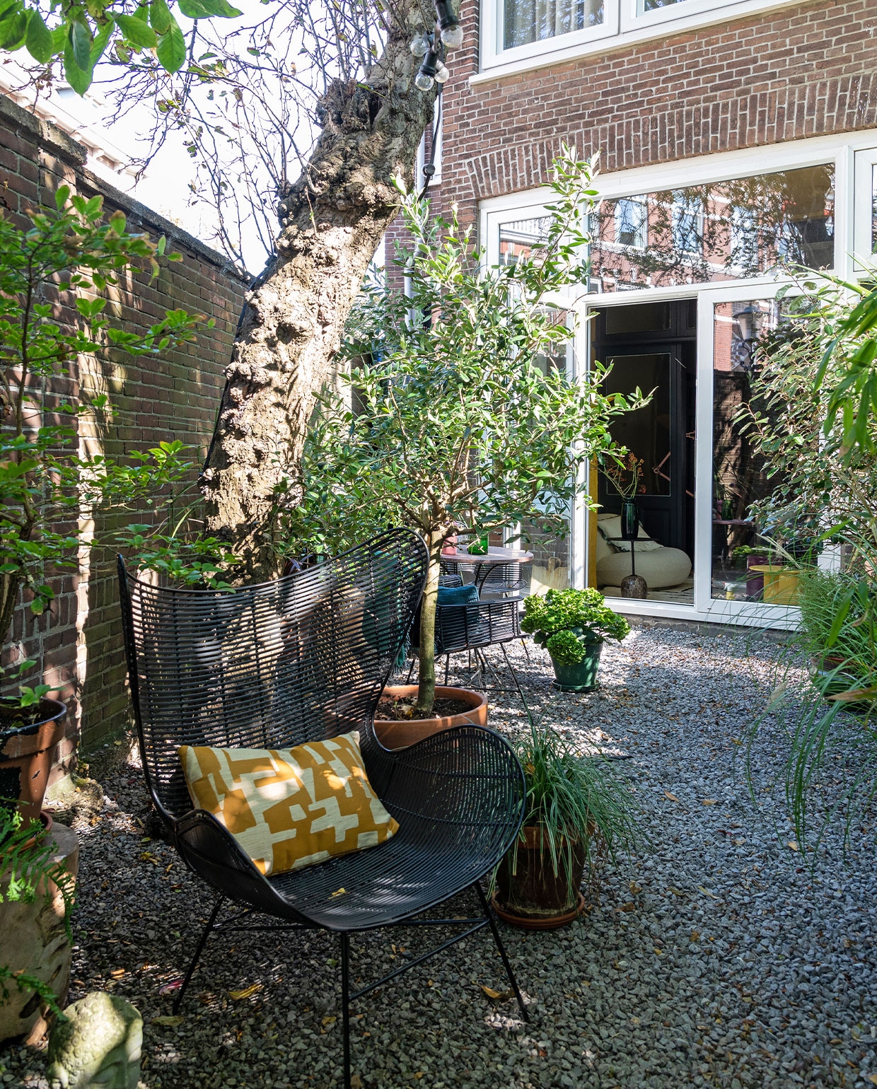 Stoel HKliving, kussen laten maken met stof van Dedar, terracotta potten tuincentrum. Op de grond grijs basalt split van verschillende grootte.
