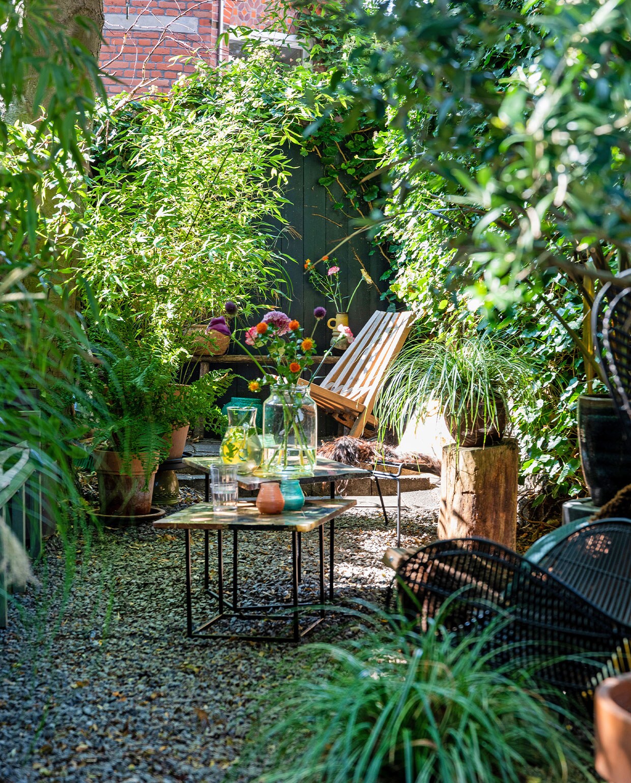 Bijzettafels en waterkaraf vintage vondsten, buitenkaarsen Bolsius, vaas vtwonen. Boomstam uit het bos. Houten ligstoel Weltevree. Terracotta potten en planten tuincentrum. Vachten Vacht van Vilt, stoel HKliving.