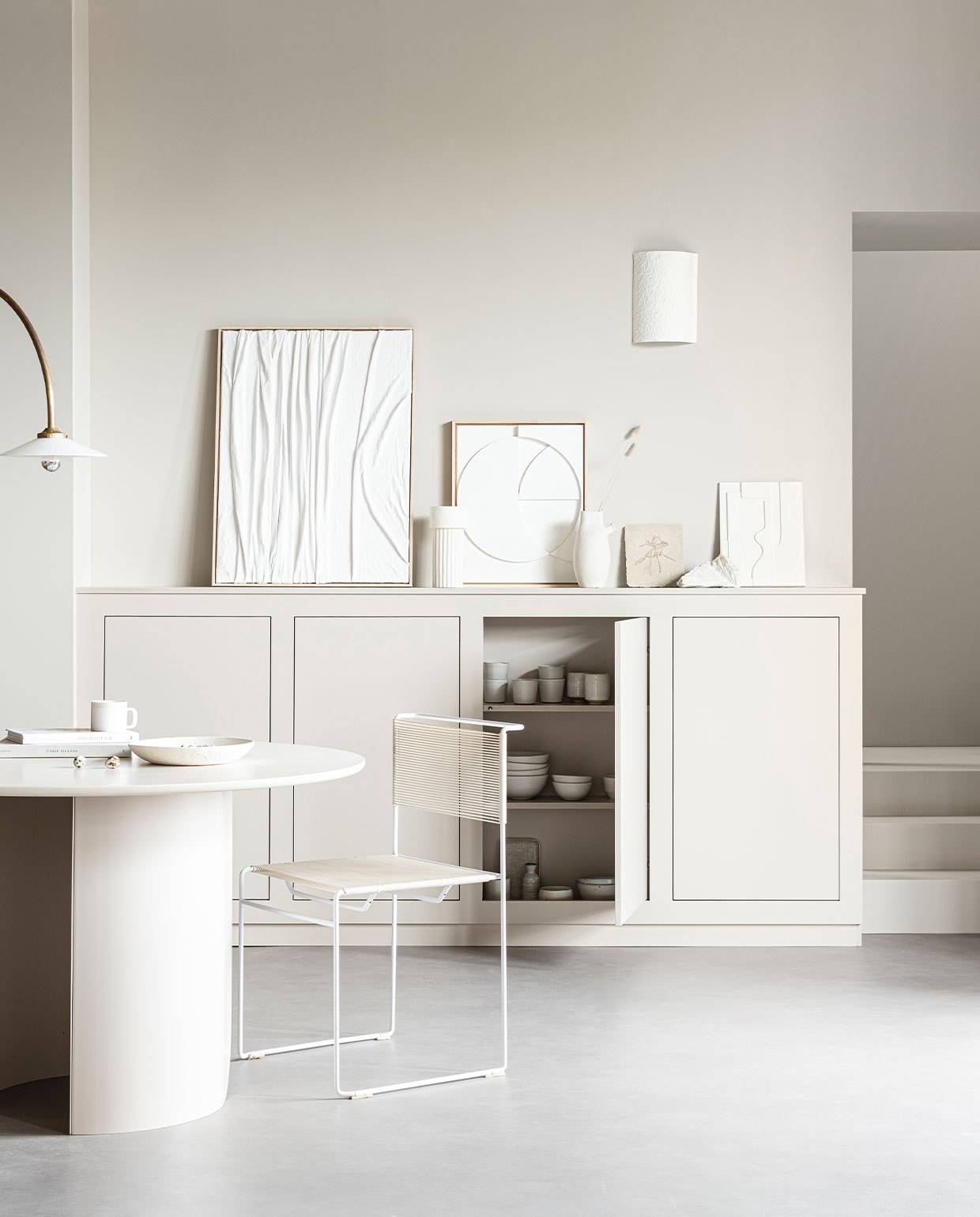 Staande lamp N°1 Brass van Valerie Object € 1890,- (justhaasnoot.nl). Witte schaal € 22,99, witte muurlamp € 99,99 (zarahome.com). Witte spaghettistoel € 175,-, wit koraal € 25,-, tegel met afdruk fossiel € 25,- (neeflouis.nl). Eettafel Plateau in kleur Sand € 1059,-, sidetable Plateau in kleur Sand € 199,- (festamsterdam.com). Linnen kunstwerk, prijs op aanvraag (instagram.com/studio.klen). Shell pot vaas van Ferm Living € 79,-, witte reliëfkunst in houten lijst van HKliving € 329,-, wit keramisch artwork van HKliving € 49,95 (vtwonen.be). Witte porseleinen vazen vanaf € 16,95 (loods5.nl). 2,5-zitsbank Rose in Danny Cream € 749,-, vloerkleed Velvet Hill Caramel € 329,- (sofacompany.com). Sidetable Plateau in kleur Sand € 199,- (festamsterdam.com). Boeken en servies privébezit. Muurverf Mushroom No.287 van LAB paint (vestingh.nl).