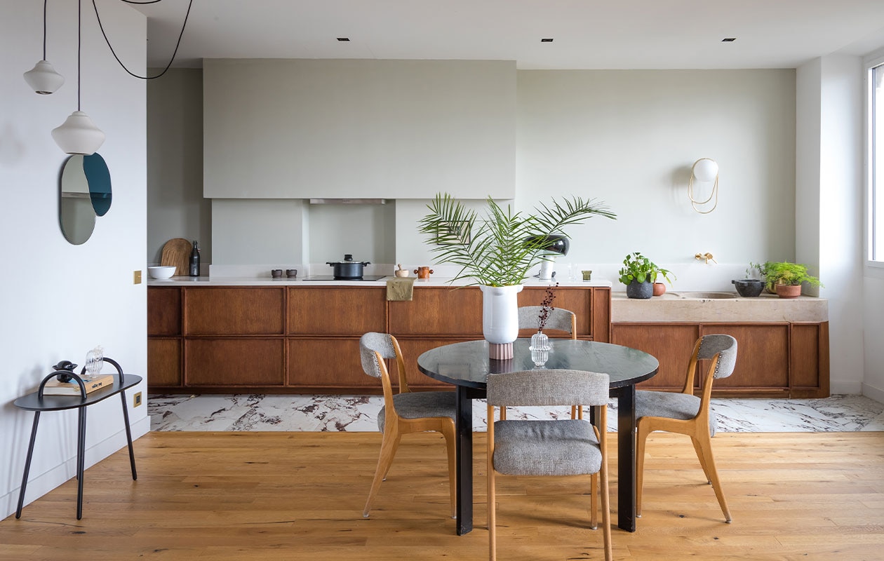 Eiken keuken uitgevoerd door timmerman, Corian werkblad. Stenen vloer Marbre van Marazzi. Vintage tafel Habitat, stoelen vlooienmarkt. Bijzettafel, wandlamp, grote vaas Oli, spiegel Maré, hanglamp voor Cfoc Paris en geurkaars Margaux Keller. Muurverf Cromarty van Farrow &amp; Ball. Overig onbekend.