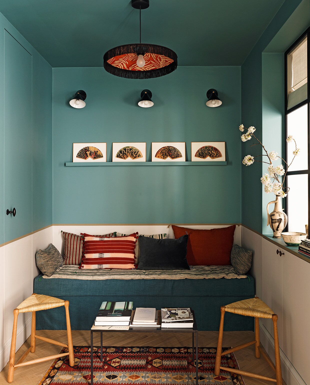 Blauwe verfkleur Mid Medici Blue, beige verfkleur Maya en kaki verfkleur Dark Stone, alles Ressource. Hanglamp Paloma Le Monde Sauvage. Wandlampen Atelier Areti. Kunstwerken op wandplank Claire Kito voor Galerie Peinture Fraîche. Kussens en salontafel Caravane. Vloerkleed Kilims Ada. Driepootkrukken Ailleurs Paris.