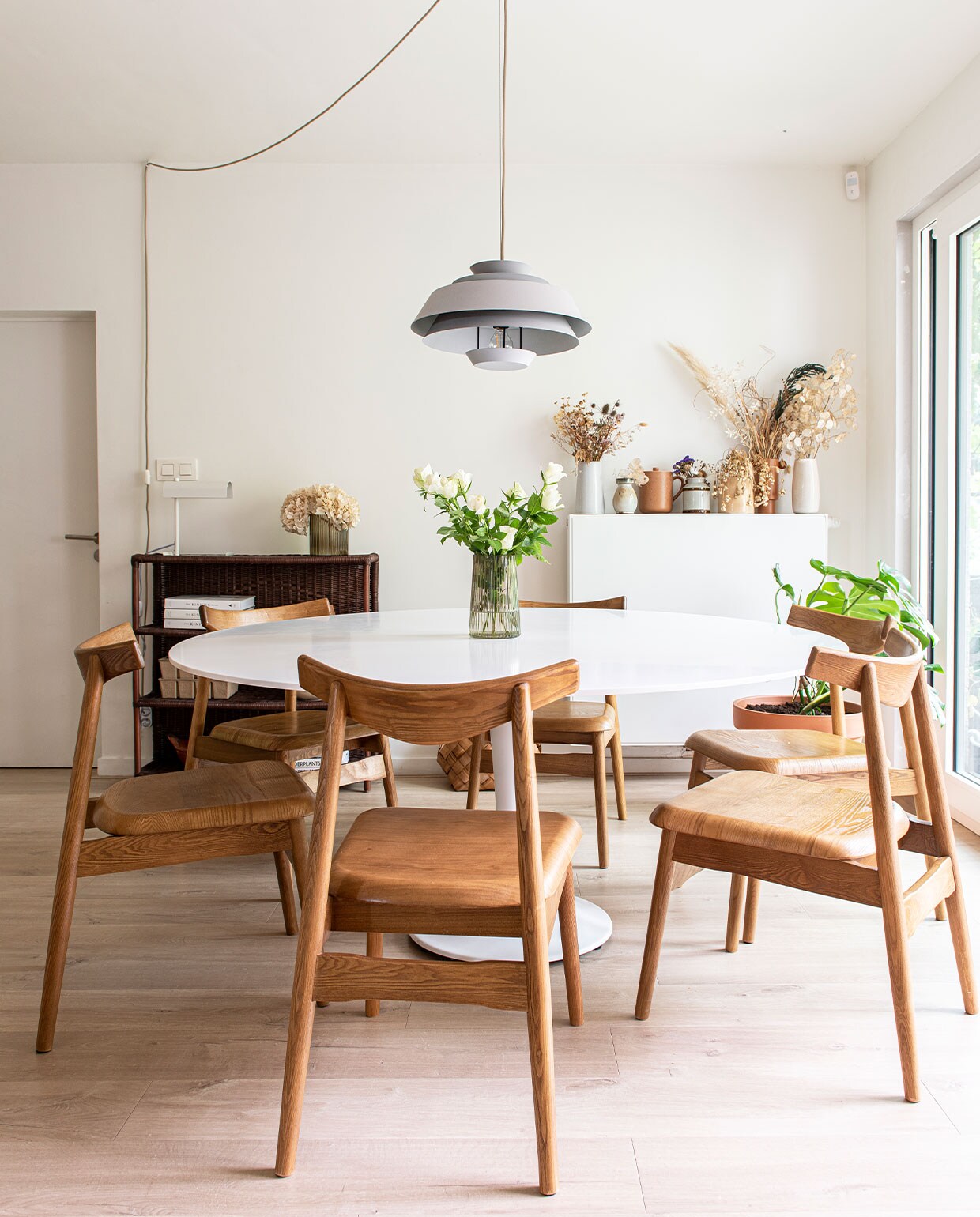 Tafelpoot van La Redoute, corian tafelblad gemaakt door timmerman Wouter Lapage, vaas op tafel Jysk, hanglamp Kwantum. Open rotan kast Merilou. Vazen op verwarming H&amp;M Home, Dille &amp; Kamille en kringloopwinkel. Stoelen, koffiekop en lamp op open kast Zara Home.