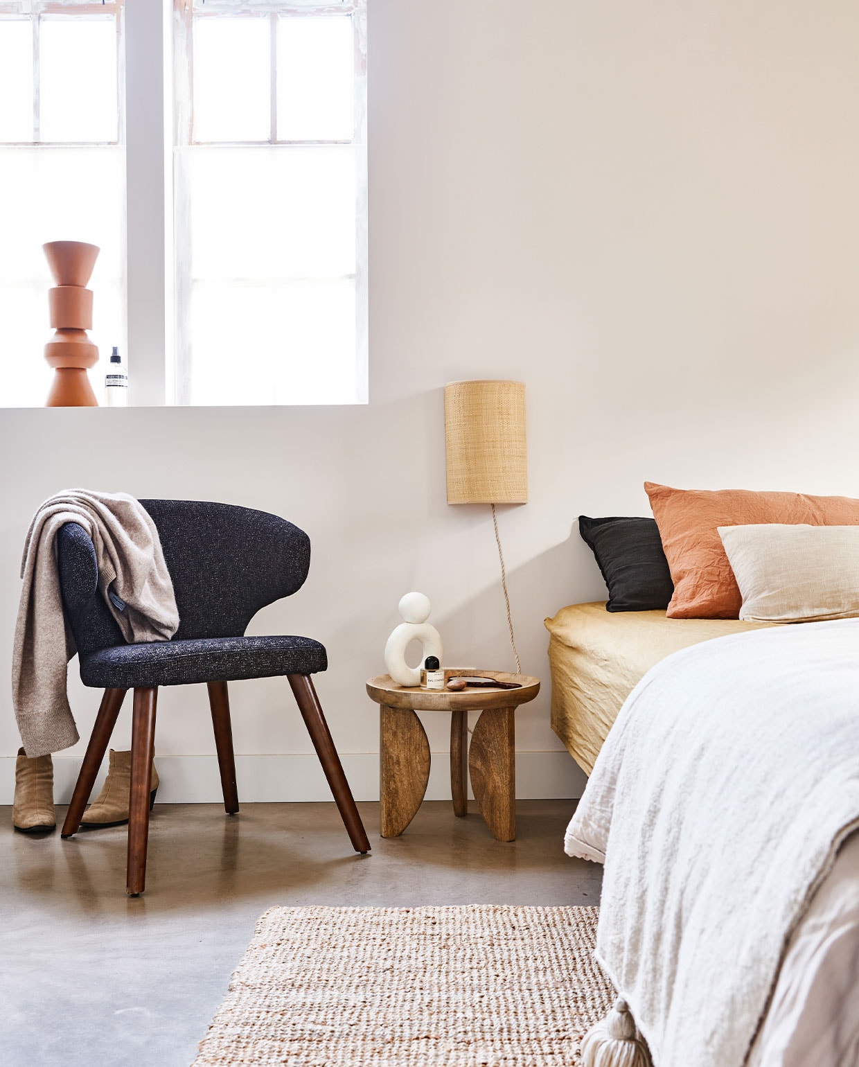 Zwarte stoel Cape, gemêleerde stof en hout, ook in blauw, 55x65x77 cm (bxdxh) € 199,-. Mangohouten bijzettafel High Heels, 40×35 cm en 70×47 cm (Øxh), set van 2 € 249,-. | m.m.v. ikea (kleed), vtwonen.nl (wit object van Urban Nature Culture), merci-merci.com (kleine kussens), pantoufle-design.nl (kussen, snoer wandlamp), hm.com (bedlinnen), christiaensen-christiaensen.be (wandlamp), marie-stella-maris.com (roomspray). Overig privébezit.