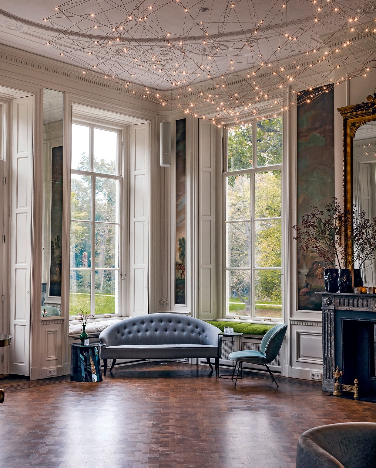 In de salon op de eerste verdieping is origineel geschilderd behang behouden. De luiken maken gordijnen overbodig, die zouden het beeld stoffig maken en het vrije uitzicht belemmeren. Sofa Paradise is een ontwerp van de Zweedse Kerstin Hörlin-Holmquist voor Gubi.