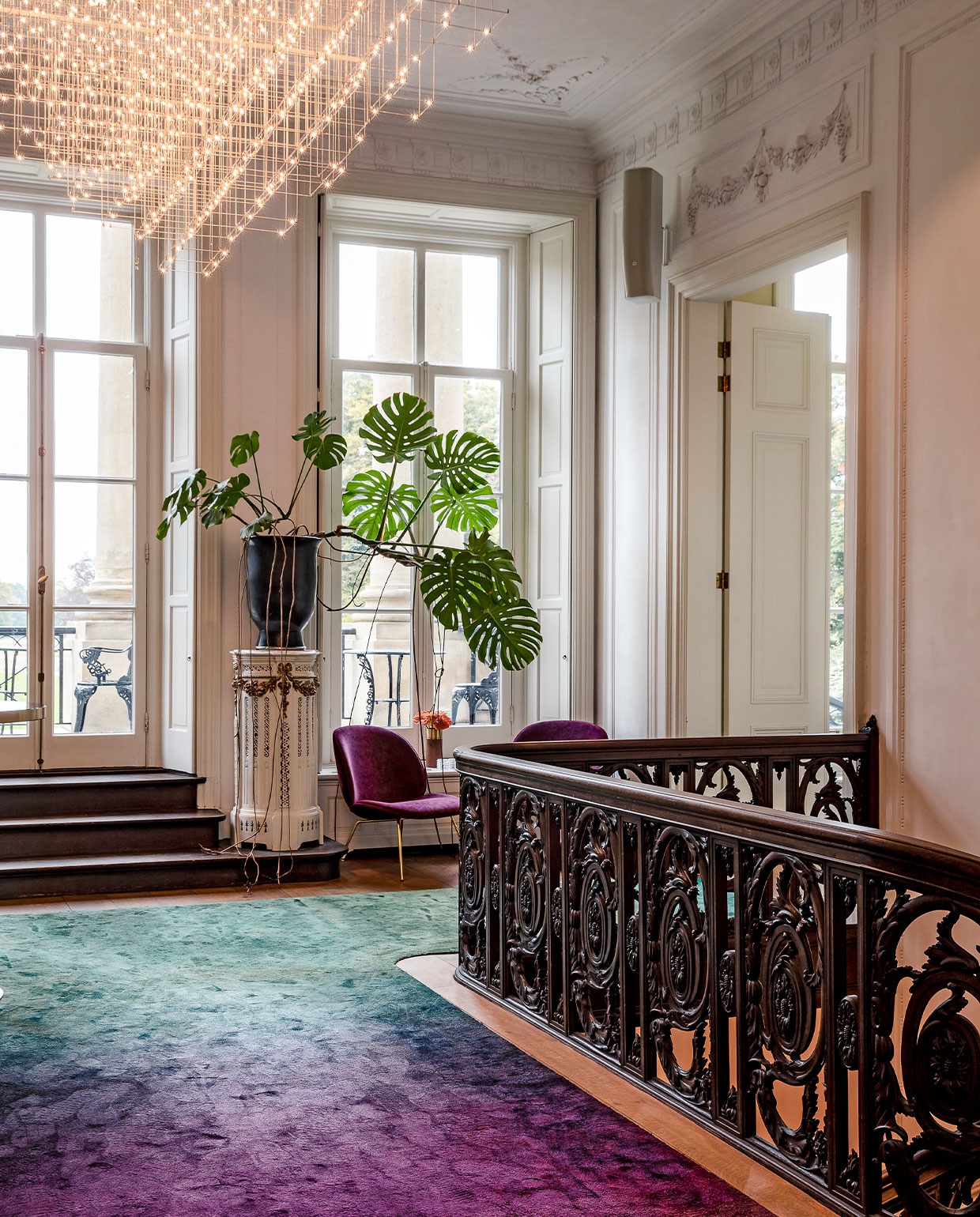 In het monumentale trappenhuis met donkere balusters, sierlijk stucwerk en plafondornamenten ontwierp Judith een loper met dégradé-effect, van hardroze naar groen. De krachtige kleuren zwakken het effect van het eikenhout af. Het spectaculaire, ijle lichtobject van Jan Pauwels maakt de balans tussen klassiek en modern compleet.