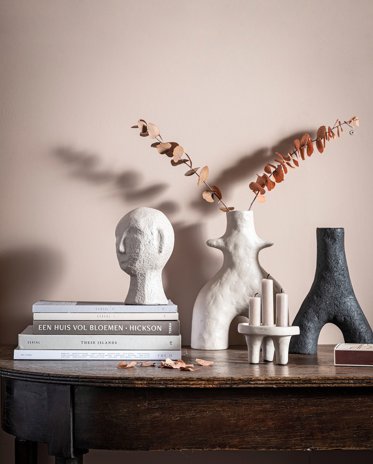 V.l.n.r. Zandkleurige sculptuurkop gemaakt van ecomix, in maat S, 13,5×12,5×20 cm (bxdxh) € 34,95. Zandkleurige vaas Twig gemaakt van ecomix, in maat M, 20x8x29 cm (bxdxh) € 44,95. Zandkleurige kandelaar met ruimte voor 3 kaarsen gemaakt van ecomix, 12x12x7 cm (bxdxh) € 16,95. Zwarte vaas Twig gemaakt van ecomix, in maat S, 18x6x25 cm (bxdxh) € 39,95. Tafel en boeken privébezit.