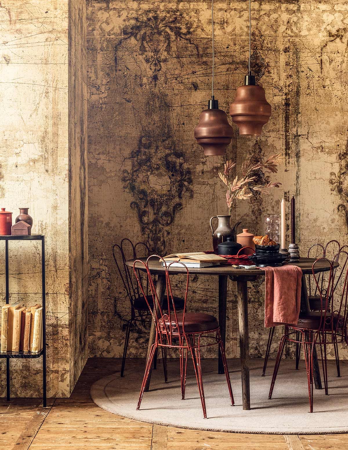 Behang Borgia (Wall&amp;decò). Hanglampen (De Weldaad). Eettafel (Homestede). Franse stoeltjes (tiltdesignenantiek). Kleed (Sofacompany). Zwart tafeltje (Bolia). Paars bakje in vorm van huis (Mobilia). Oranje potje met oor, paars vaasje (MaisonNL). Glazen vaas (Homestede). Dienblad (Linda’s hoekje). Kunsttak (De Weldaad). Zwarte schaaltjes (Pieter &amp; Tosch). Kandelaars (Things I Like Things I Love). Potten (H&amp;M Home). Servet en kaars privébezit.