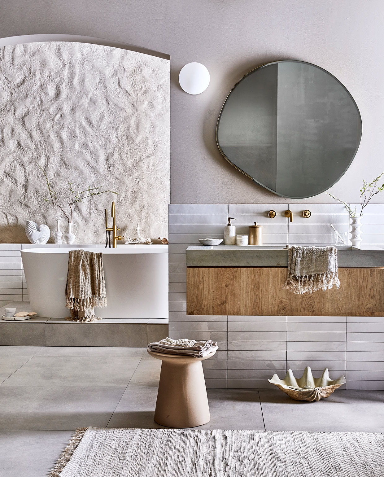 Vloertegel Mold XL Cement, 90×90 cm. Wandtegel achter wastafel Marrakesh, kleur Nieve, glans, 6,5×40 cm (lxb). Wastafel Tank, beton, kleur Concrete, 10x120x46 cm (hxbxd). Onderbouwkast Cube, eikenhoutfineer, kleur Oak, 30x120x43,5 cm (hxbxd). Wandkraan Flame, kleur Bronze, inbouwdeel. Bad Tub. Badmengkraan Flame, kleur Bronze, vrijstaand M.m.v. vtwonen.be (muurverf kleur Flax, spiegel Ferm Living, wafelhanddoek Marc O’Polo), hkliving (kruk, kleine witte vazen), nordal.eu (grote schelp, schelpvormige vaas, linnen badlakens, marmeren zeepdispenser), weldaad.com (marmeren schaaltje), hm.com (loper, grote marmeren schaal op vloer). De achterwand kreeg stuc effectief in kleur Flax van vtwonen (gemaakt door setbouw Milo Kol).