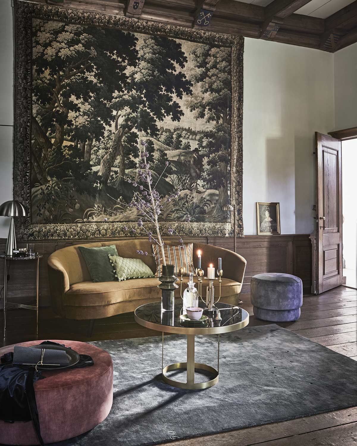 Okergele sofa London (Sissy-Boy). Salontafel, vaas, vierarmige kandelaar, kandelaar voor stompkaars, glas (Nordal). Vloerkleed en poefs (4x6sofa). Hoge bijzettafel met marmeren blad van Gubi (Goeds). Groene kussenhoes, zijden kussenhoes met balletjes, gestreepte kussenhoes (H&amp;M). Glazen karaf soortgelijk prijs op aanvraag (Prinsheerlijk Antiek). Goudkleurige lamp (Hübsch Interior). Roze kom, groen bordje (Anouk Kramer). Notitieboek (Madam Stoltz). Overig privébezit.