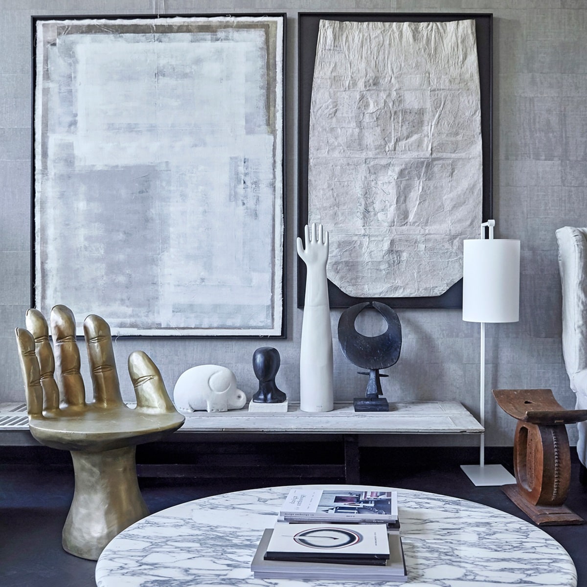 Behang Atelier d’Artiste Elitis via Loggere Wilpower. Gouden stoel/hand Pols Potten, stalamp Serge Mouille. Tafel antiek luik met los vintage onderstel. Witte olifant en witte hand vintage via It Flinkeboskje, overige vintage accessoires en Japanse vintage rijstzak in zwarte baklijst via Nrdrhvn91. Zwart Object Ming Stylemeister. Schilderij Laura de Wilde. Tafel op voorgrond Knoll.