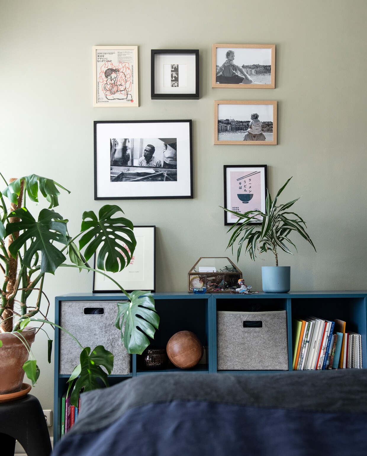 Muurverf French Gray van Farrow &amp; Ball. Kast Ikea, grijze dozen Hema. Vintage leren bal Merci Parijs. Print droogbloemen gekregen van vrienden. Sieradendoos Sissy-Boy. Bloempot Elho. In lijsten: privéfoto’s, Miles Davis van Yellow Korner, print van 21st Century Museum of Modern Art Kanazawa, Miso-print van Desenio, gedroogde tak cadeau gekregen. Blauw beddengoed Crisp Sheets. Overig onbekend.