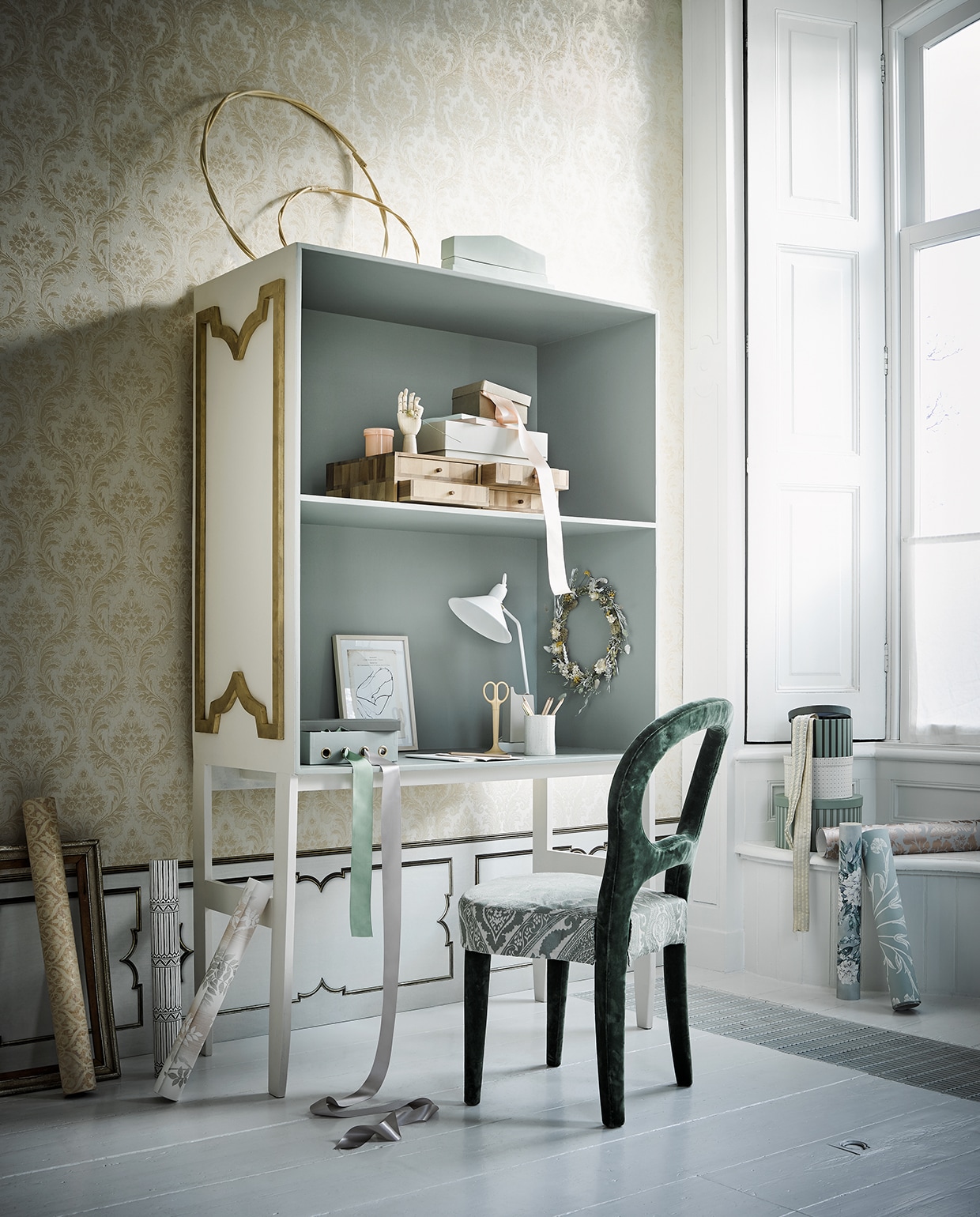 Behang aan de bovenzijde van de wand, Trianon Vol. II388531 (eijffinger.com). Lambrisering: behang MRV-25 Wainscoting van Mr. &amp; Mrs. Vintage in de kleur White, 48,7×487 cm (nlxl.eu). Alle behangsoorten van Designers Guild en Osborne &amp; Little in de vensterbank en op de grond , behang van Nina Campbell, per meter € 74,80 (wva). Bekleding van de stoelzitting van Nobilis (wva.nl). Secretaire (com-anders.). Verf aan de buitenkant van de kast in de kleur Dimity van Farrow &amp; Ball; binnenkant Blue Gray van Farrow &amp; Ball (deruamsterdam). Groene fluwelen stoel (covanderhorst). Siervorm op kast van HKliving € 69,95 (deens). Houten hand in de kast, roze glazen potje, kartonnen doos op houten box, schaar, plakband-apparaat, potloden, gouden pen (hay-amsterdam.com). Houten ladekastje (homestede). Groene doos met vier nestels, ronde dozen in drie maten (sostrenegrene.com). Witte lamp (loods5). Kunstwerk (tinystories). Bloemenkrans (maisonnl.com). Overig privébezit.