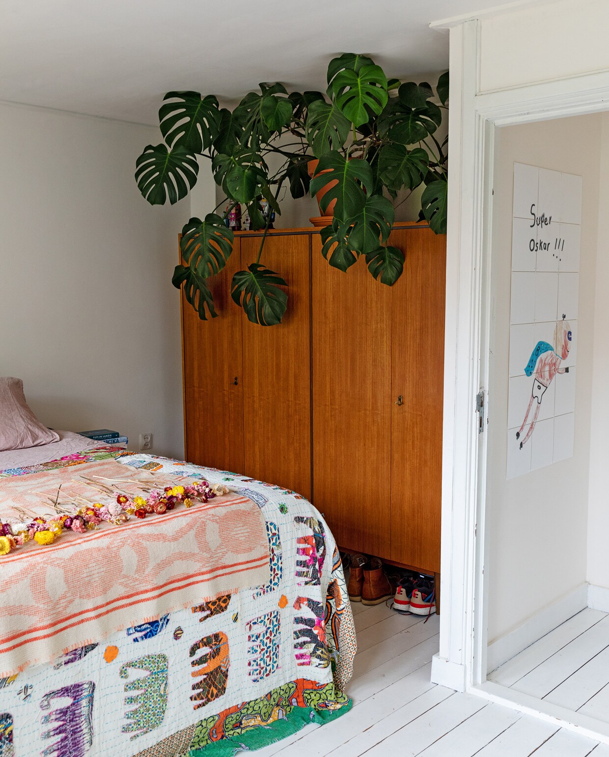 Bruine kast Marktplaats. Deken met olifanten souvenir uit India. Roze plaid met gedroogde bloemen Loesje van Herp. Tekening in de gang gemaakt door Oskar. Gatenplant Monstera Sissy-Boy.
