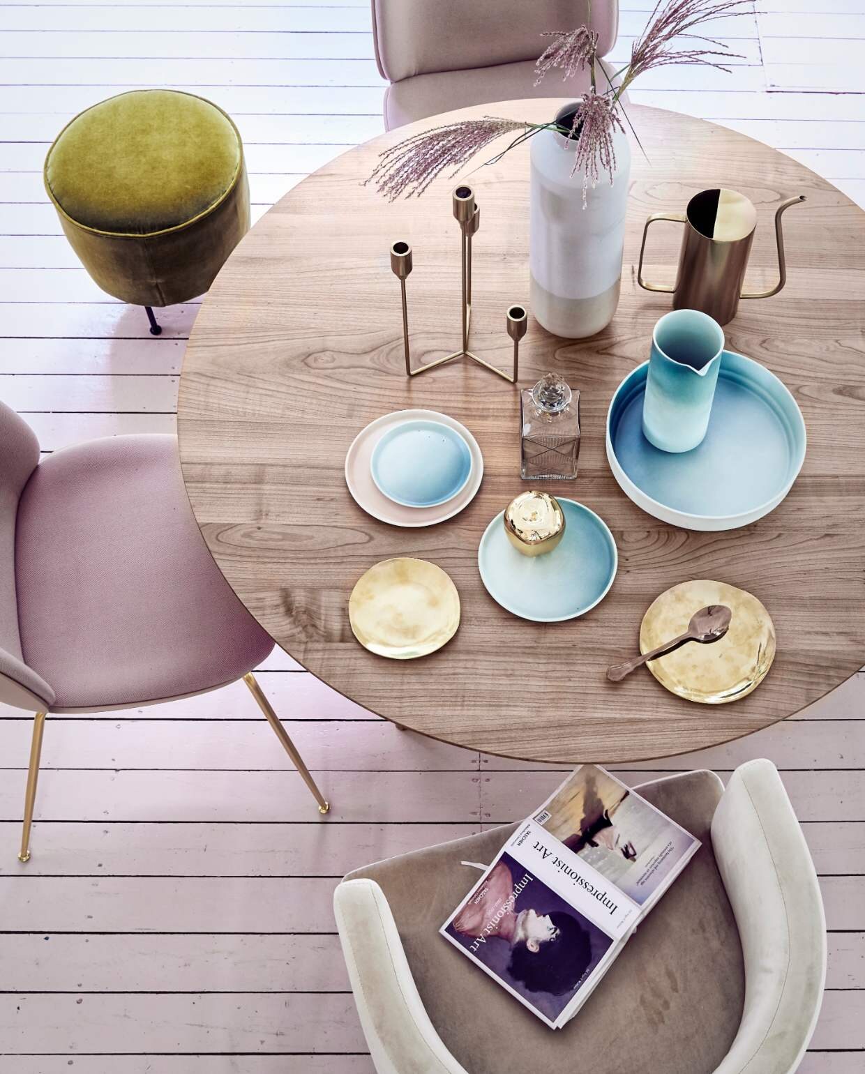 Romantische woonstijl: ronde eettafel met pastel servies en roze velvet stoelen.