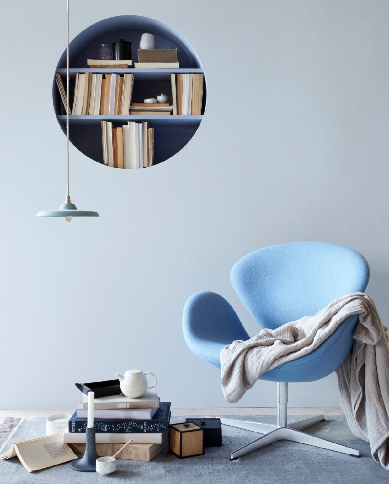 Design woonstijl: blauwe stoel, ronde boekenkast en pastelkleuren.