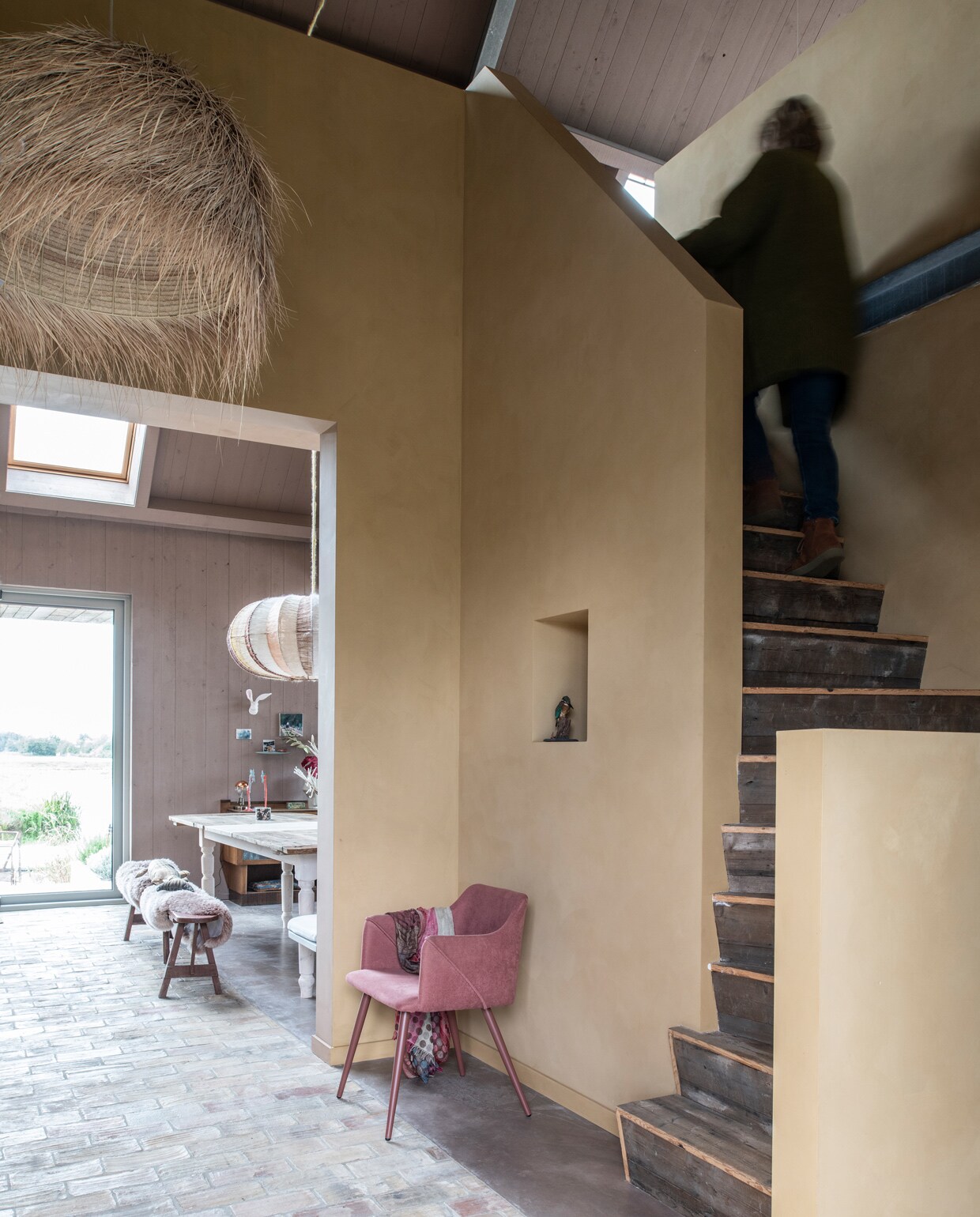 Trap eigen ontwerp en gemaakt door Scheffelaar. Zeegras hanglamp Couleur Locale. Kuipstoel Fonq. In de nis een opgezette ijsvogel. Op de muur natuurlijke kalkverf in kleur Provincial Gold van Pure &amp; Original.