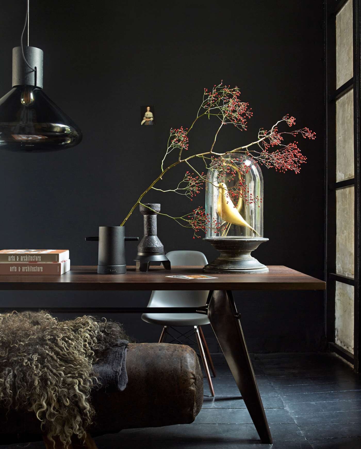 Klassieke woonstijl: donker interieur grote eettafel met stolp vaas en hanglamp.