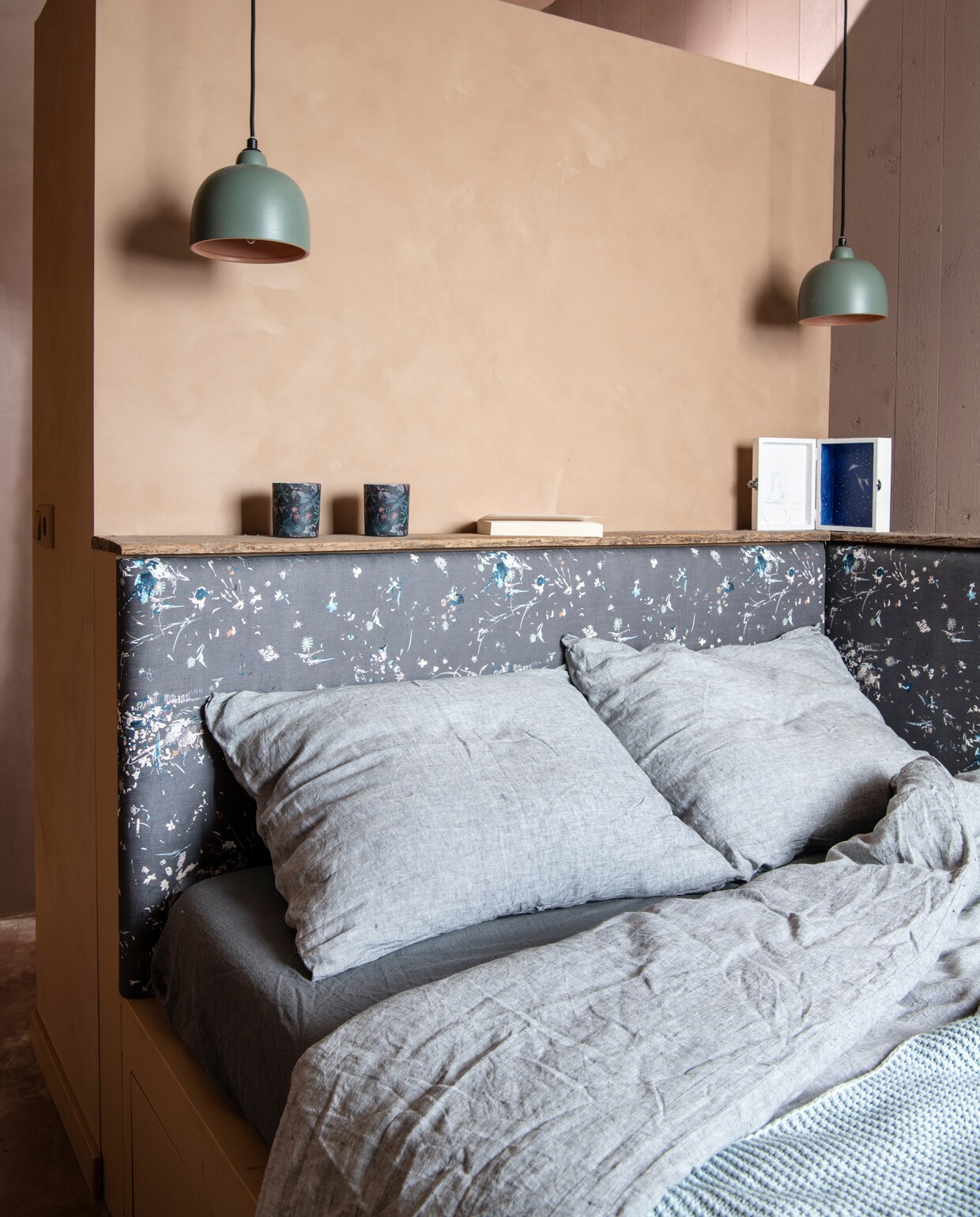 Bed is eigen ontwerp en bekleed met Japanse stof, gekocht via Etsy. Dekbedovertrek By Mölle. Plaid Ikea. Hanglampjes Serax. Wit kijkdoosje van kunstenaar Tisja Kljakovic Braic. Potjes Sissy-Boy. Op de muur natuurlijke kalkverf in de kleur Artisan Tan van Pure &amp; Original Paint.