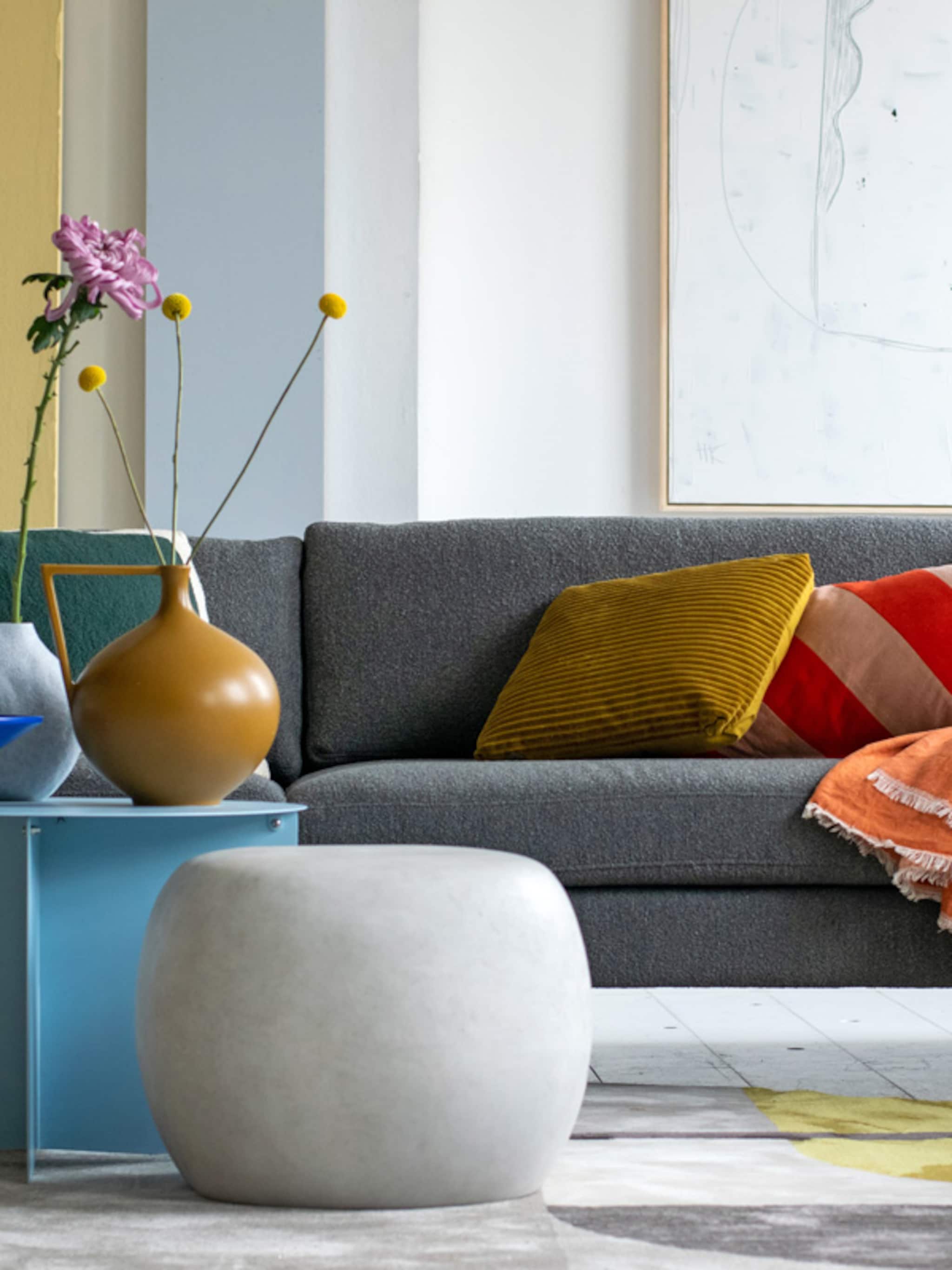 stylingtips van marianne kleur geven aan de grijze zetel