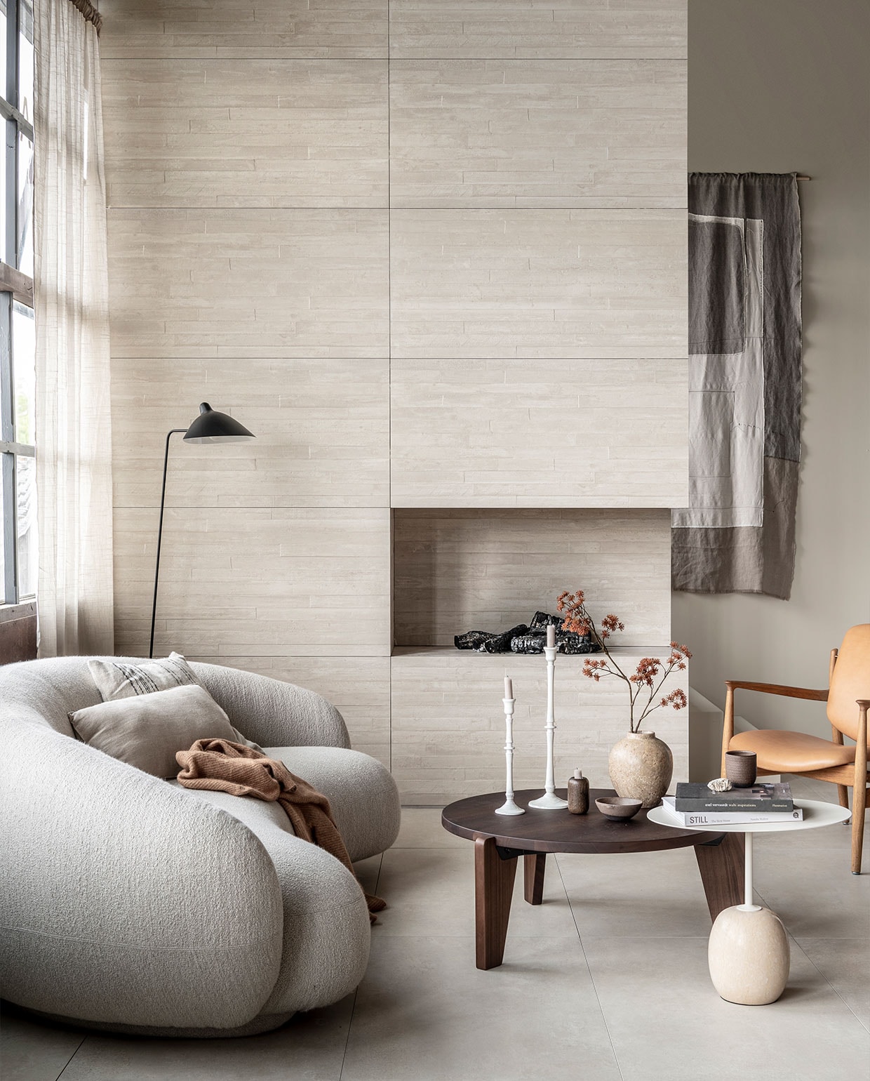 Op de wand: wandtegel Raw Casa Decor 3D in kleur Sand, 60×120 cm, per m² € 69,-. Op de vloer: vloertegel Raw in kleur Sand, 60×120 cm, per m² | M.m.v. justhaasnoot.nl (staande lamp, bank Julep van Tacchini, salontafel Guéridon Bas van van Vitra, witte bijzettafel Lato van &amp;Tradition, fauteuil van hout met leer van House of Finn), zarahome.com (witte metalen kandelaars, stenen vaas), suhka.nl (textielkunstwerk, kom en mok). Overig privébezit.