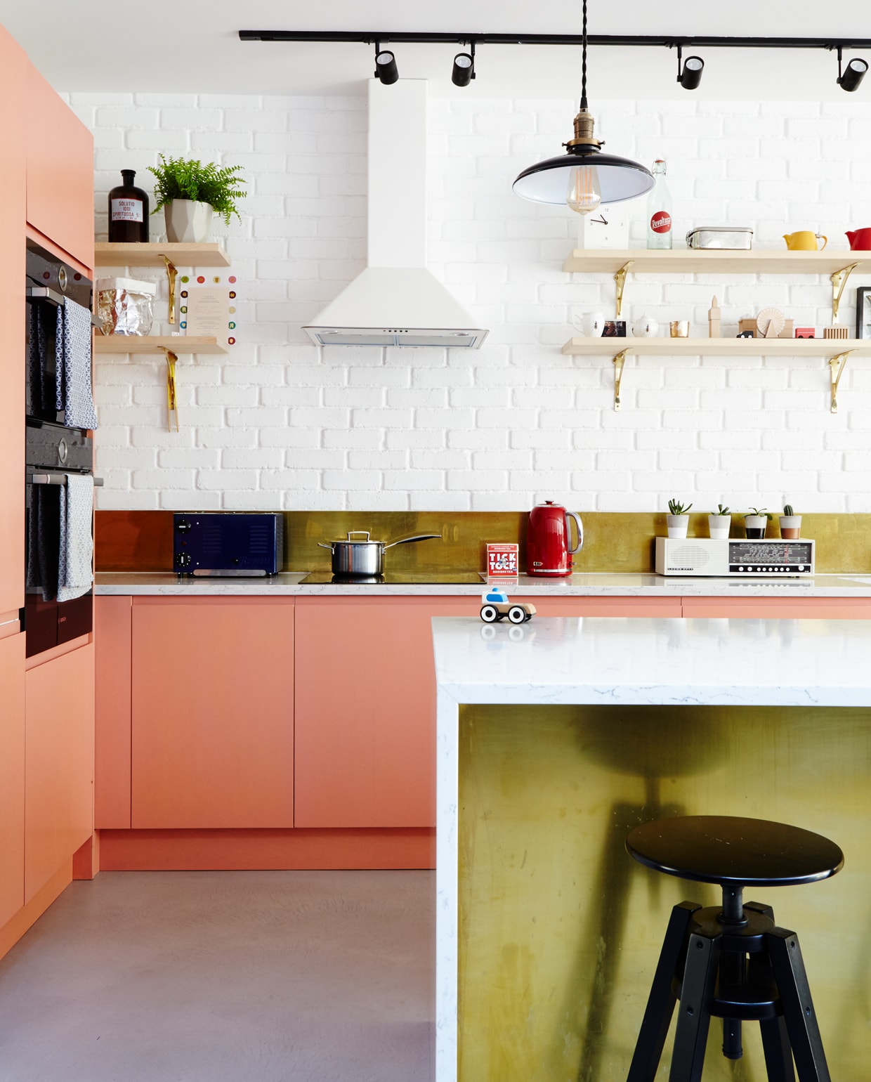 Het perzikkleurige roze van de keukenkasten is ‘afgekeken’ van een Acne draagtas. De geverfde frontjes werden op Ikea onderkastjes geplaatst. De koperen spatwand is een verrassende combinatie met de wit geschilderde baksteenstrips.