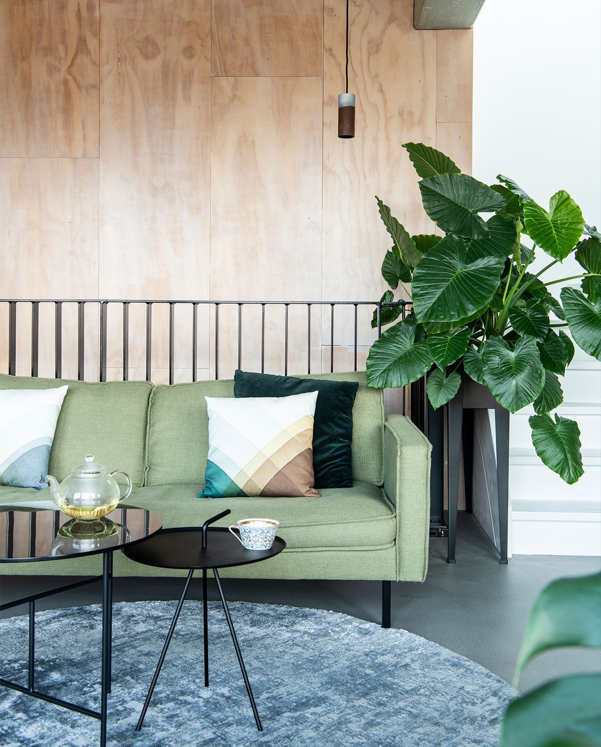 Bank Loods 5 Design. Herringbone kussens van Vitra via Groen + Akker. Groen kussen en plantenstandaard Intratuin. Vloerkleed Gusta. Hoge bijzettafel Loods 5. Lage bijzettafel Woood. Vloerlamp Zuiver. Hanglamp Roest van Van Joost voor Graypants. Theepot Bredemeijer. Theekop vintage. Plantenstandaard Intratuin. Wandbekleding underlayment platen.