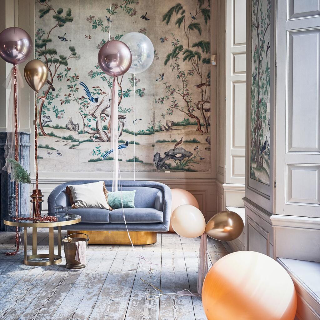 Ballonnen (partyballoon). Tule (boerenbonthal). Franjegordijn (slinger). Glazen salontafel 45×80 cm, vaas, fluwelen kussen met franjes (nordal.eu). Groen kussen, grijze champagneglazen met ribbel van Ferm Living (vtwonen.be). Zilvergrijze fluwelen bank van Jonathan Adler (ankevangoor.com). Champagnekoeler (iblaursen.dk).