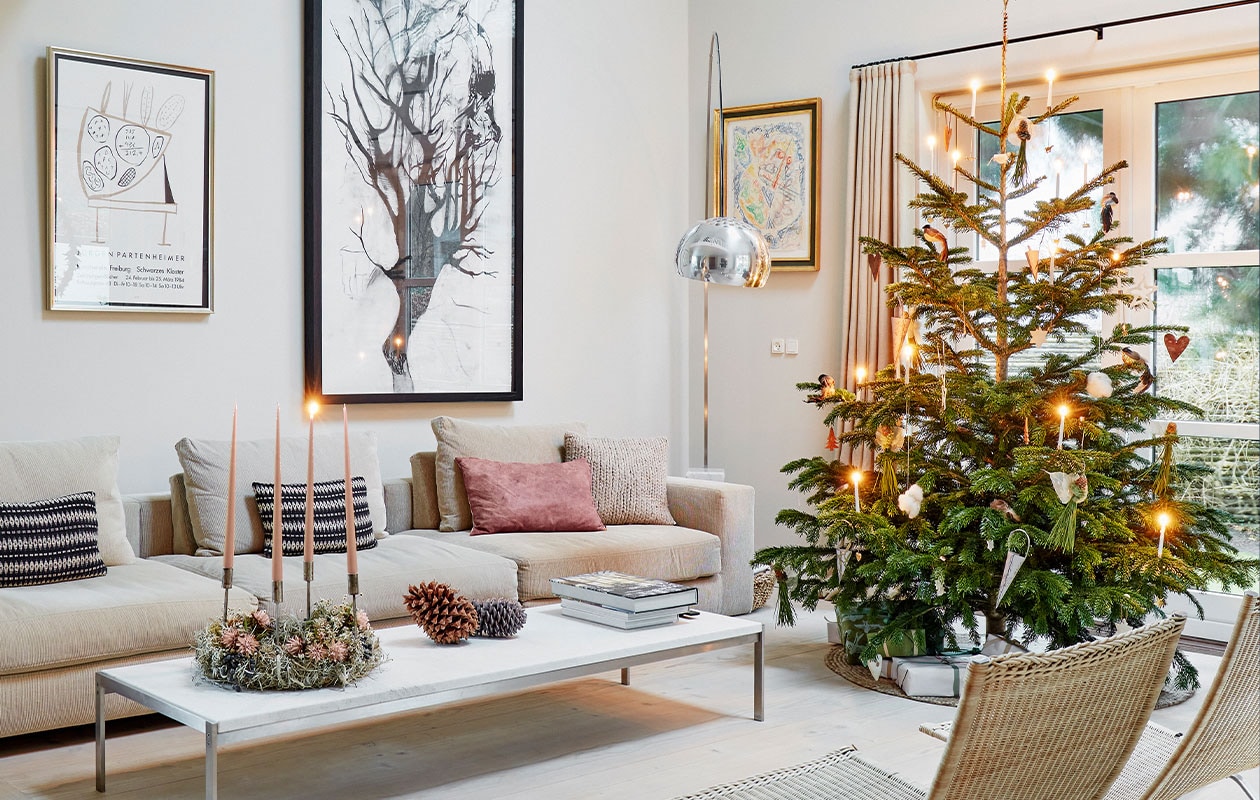 Bank Baseline van Eilersen, kussens Tapet-Cafe. Marmeren koffietafel Poul Kjærholm, kerstkrans met kaarsen gemaakt door Malou Karberg en Henrietta. Inkttekening boven bank Cathrine Raben Davidsen, kunstwerk links naast raam Egill Jacobsen. Lamp Arco van Achille &amp; Castiglioni voor Flos.